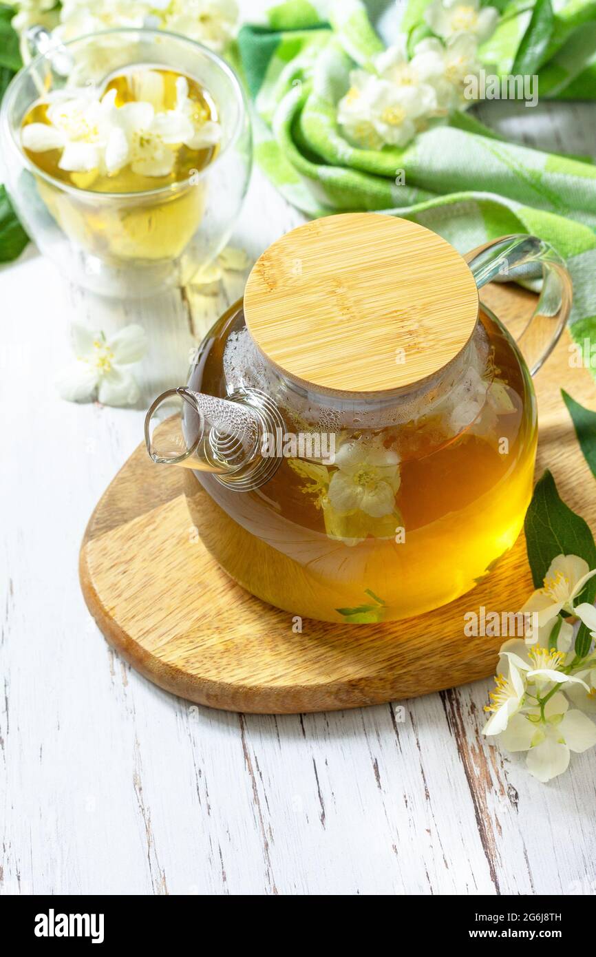Tisane thérapeutique. Thé au jasmin chaud avec fleurs de jasmin dans une théière en verre sur une table rustique en bois. Copier l'espace. Banque D'Images