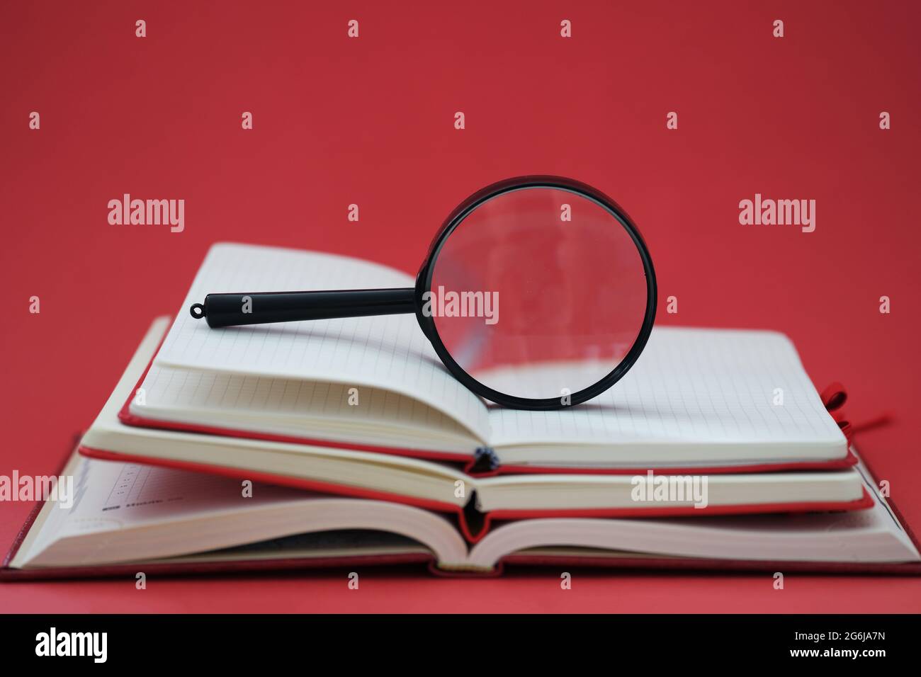 Loupe sur pile de livres sur fond rouge Banque D'Images