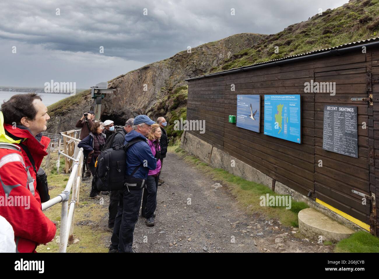 Wales touristes; personnes visitant Ramsey Island RSPB sur une promenade étudiant les panneaux d'information, Ramsey Island, Pembrokeshire Wales UK Banque D'Images