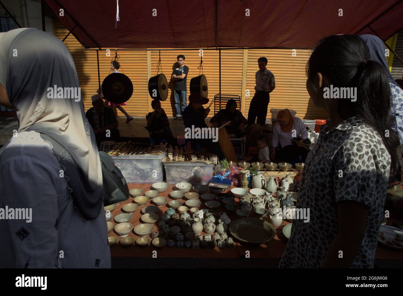 Les gens qui marchent dans la rue Gaya, passant devant un vendeur de porcelaine, de gongs et d'antiquités pendant le marché du dimanche de Gaya. Kota Kinabalu, Sabah, Malaisie. Banque D'Images