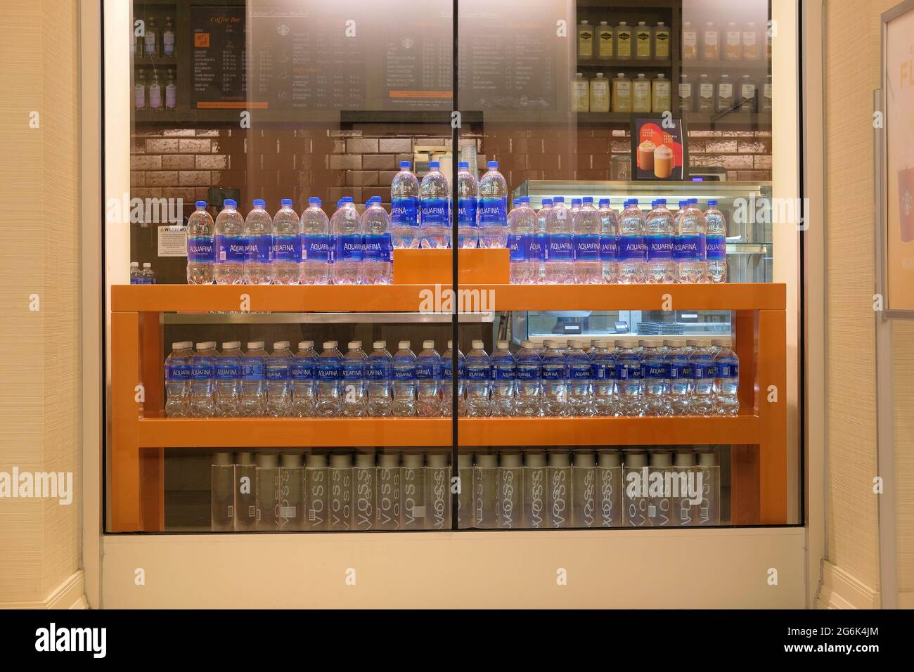 Bouteilles en plastique Aquafina et Voss exposées dans une fenêtre Starbucks de Californie ; lignes d'eau en bouteille purifiée et artésienne mises en vente. Banque D'Images
