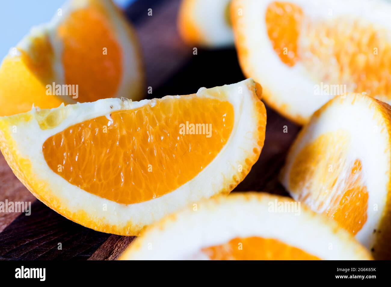 Coins orange sur une planche à découper de cuisine sur fond bleu Banque D'Images