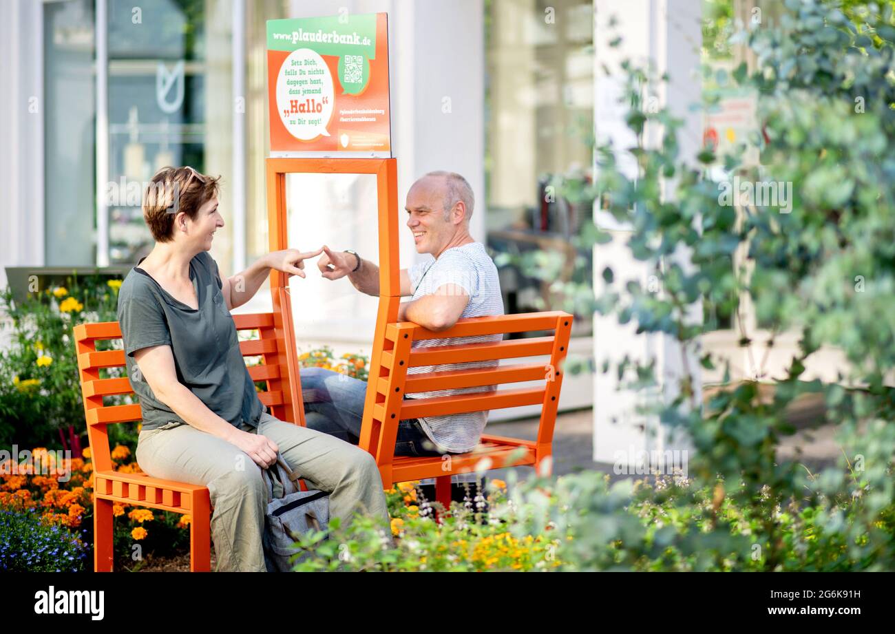 Oldenburg, Allemagne. 03ème juillet 2021. Doris et Ansgar d'Ochtrup s'assoient sur un banc de chat dans le centre-ville d'Oldenburg. Les bancs corona-conformes sont équipés d'un panneau de verre entre les sièges et sont destinés à inviter les gens à engager la conversation avec les autres. Depuis mai, dix bancs de chat ont déjà été installés à divers endroits de la ville. Credit: Hauke-Christian Dittrich/dpa/Alay Live News Banque D'Images