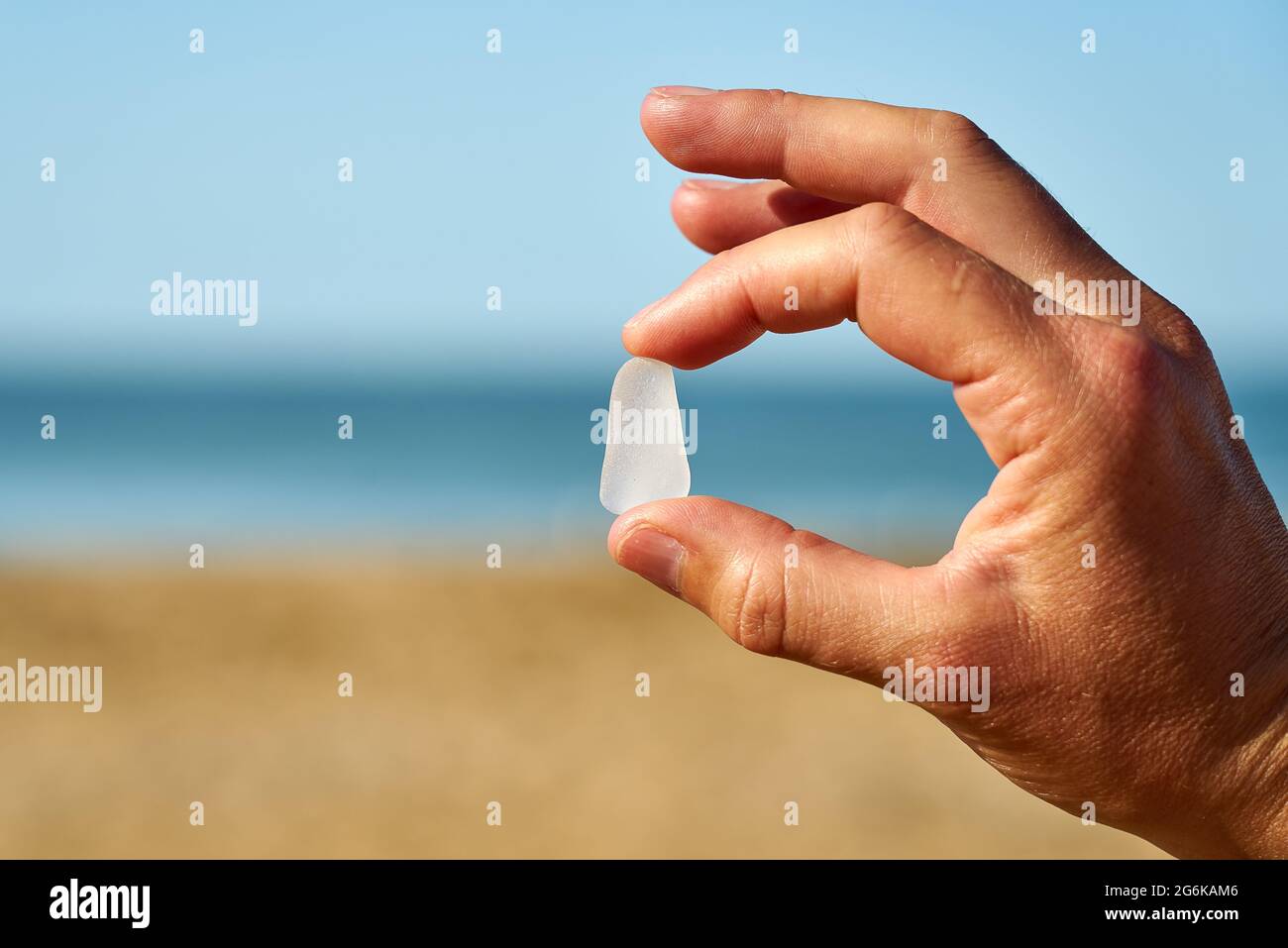 Une personne tient un seul morceau de verre de mer blanc entre son doigt et son pouce Banque D'Images Une personne tient un seul morceau de verre de mer blanc entre son doigt et son pouce Banque D'Images
