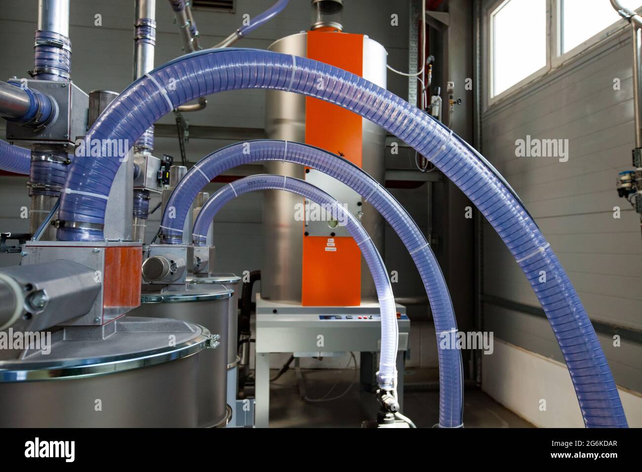Atyrau,Kazakhstan:usine de Chevron. Gros plan de la ligne de production des tuyaux en plastique photo.équipement gris,flexibles en silicone bleu transparent ondulé,trémie orange. Banque D'Images
