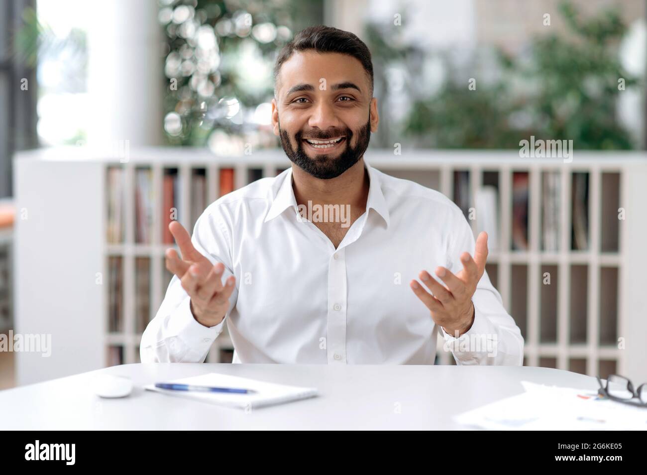 Amical positif confiant personne d'affaires ou mentor indien, communiquer avec un collègue ou un client lors d'une conférence téléphonique, regarde la caméra, gestuelle avec les mains, sourires agréablement, avoir un entretien en ligne Banque D'Images
