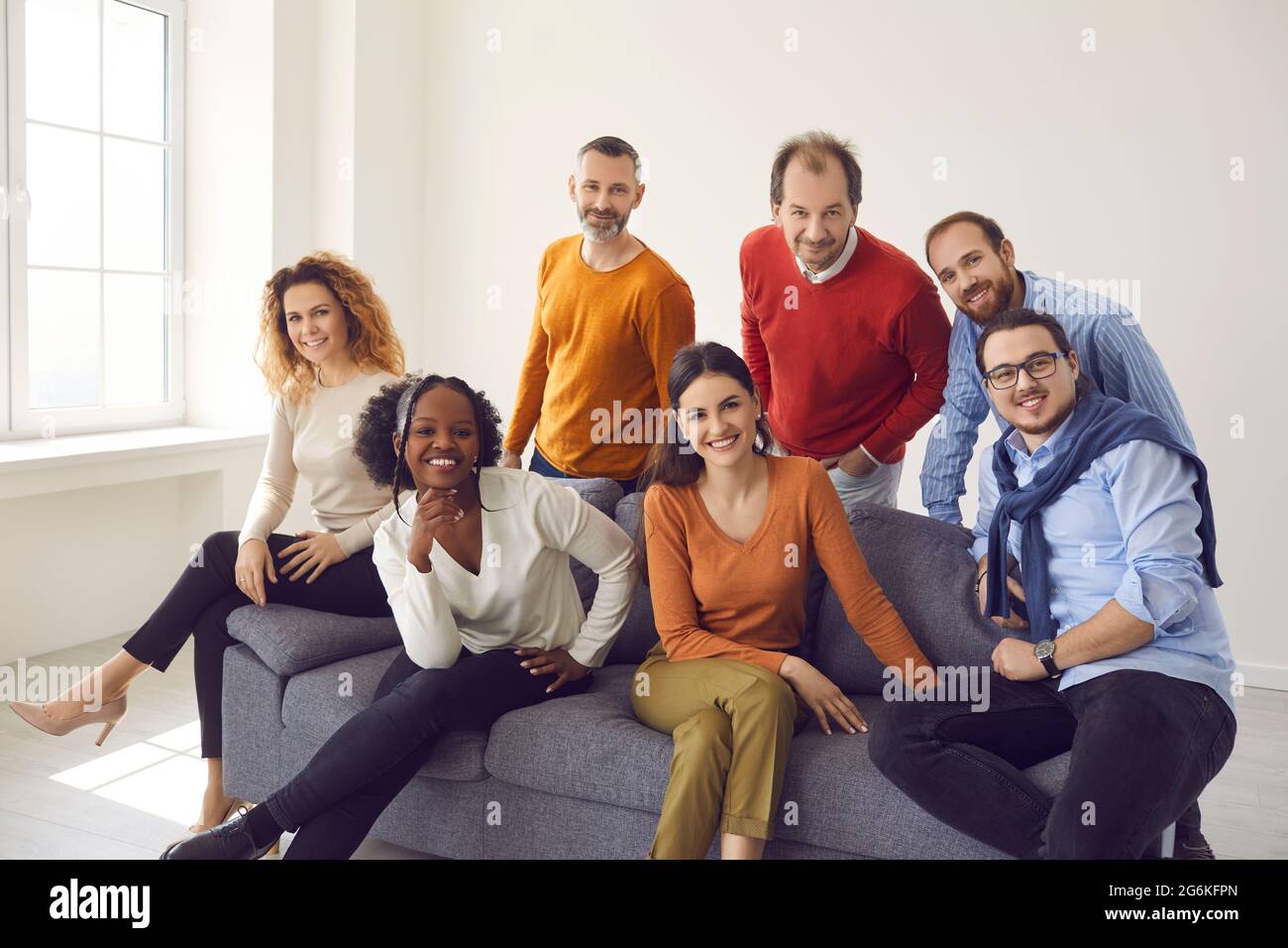 Groupe de personnes d'âge et d'ethnicité différents assis sur le canapé regardant la caméra Banque D'Images