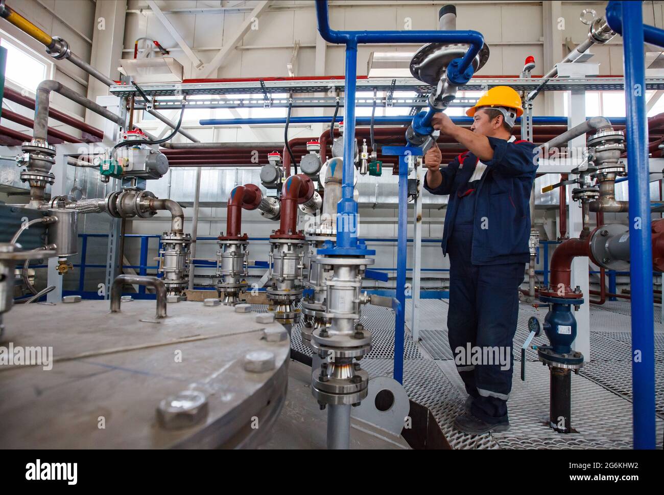 Atyrau,Kazakhstan-mai 21,2012: Usine chimique Rauan Nalco. Technicien asiatique dans le système de pompage de hardhat jaune d'accord de réacteur chimique. Atelier Banque D'Images