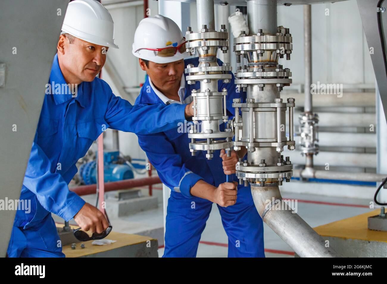 Atyrau,Kazakhstan-mai 21,2012: Usine chimique Rauan Nalco. Deux ouvriers asiatiques assemblant un système de tuyaux haute pression. Tubes et raccord en acier inoxydable Banque D'Images