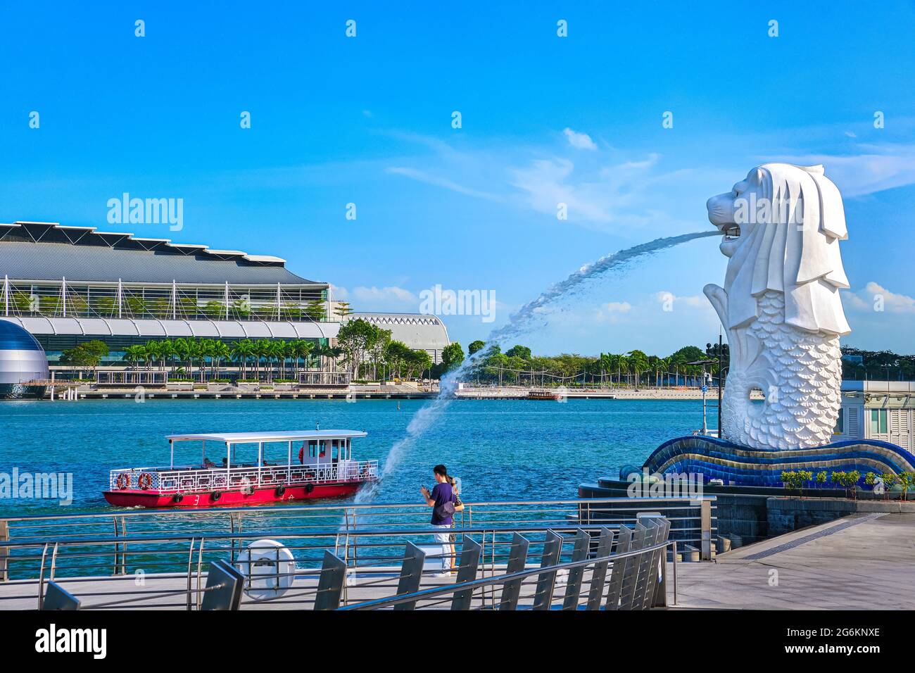 Le bateau touristique passe par Merlion, symbole de Singapour, sur la rive de la baie de Marina. Quelques adultes méconnaissables prennent des photos ou font des selfies avec une vue Banque D'Images