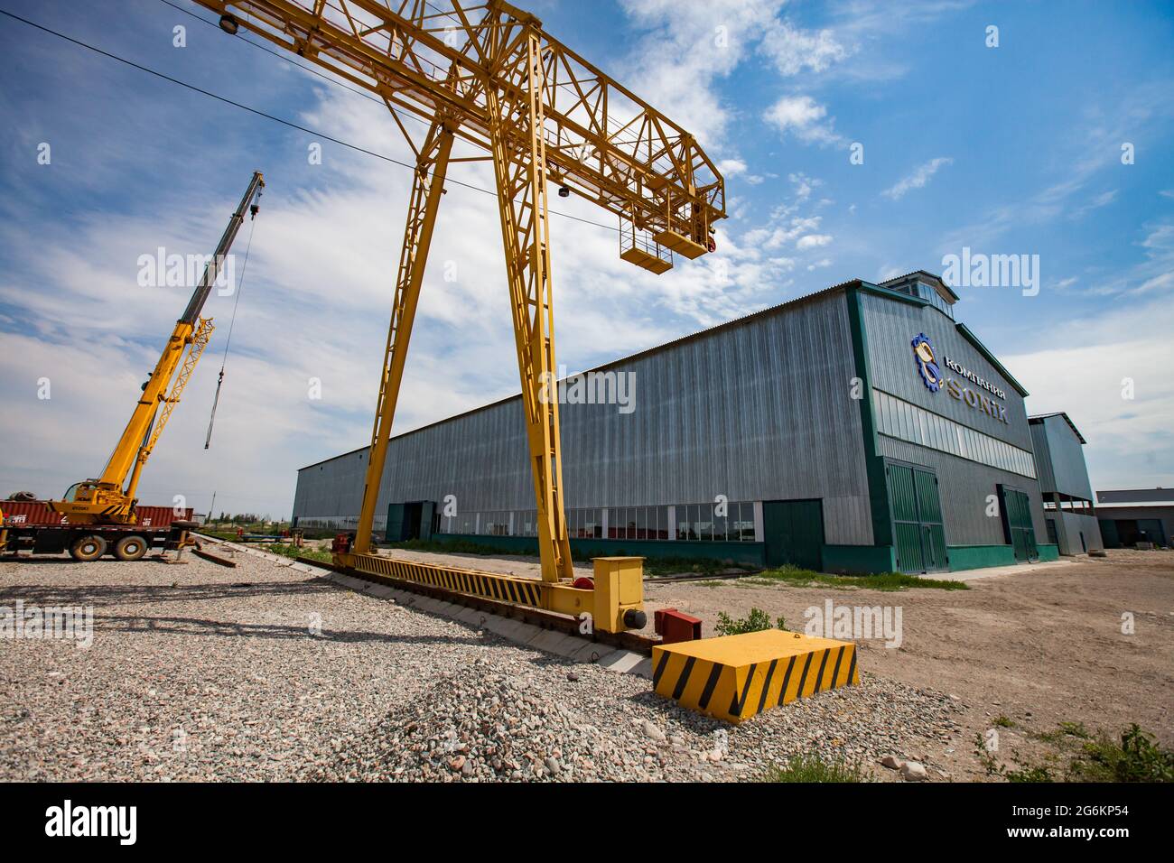 Région d'Almaty, Kazakhstan-juin 06,2012: Zone industrielle de DAMU. Nouveau bâtiment de l'usine de Sonik. Portes vertes, chemin de fer, portique jaune et grues de camion à gauche. S Banque D'Images