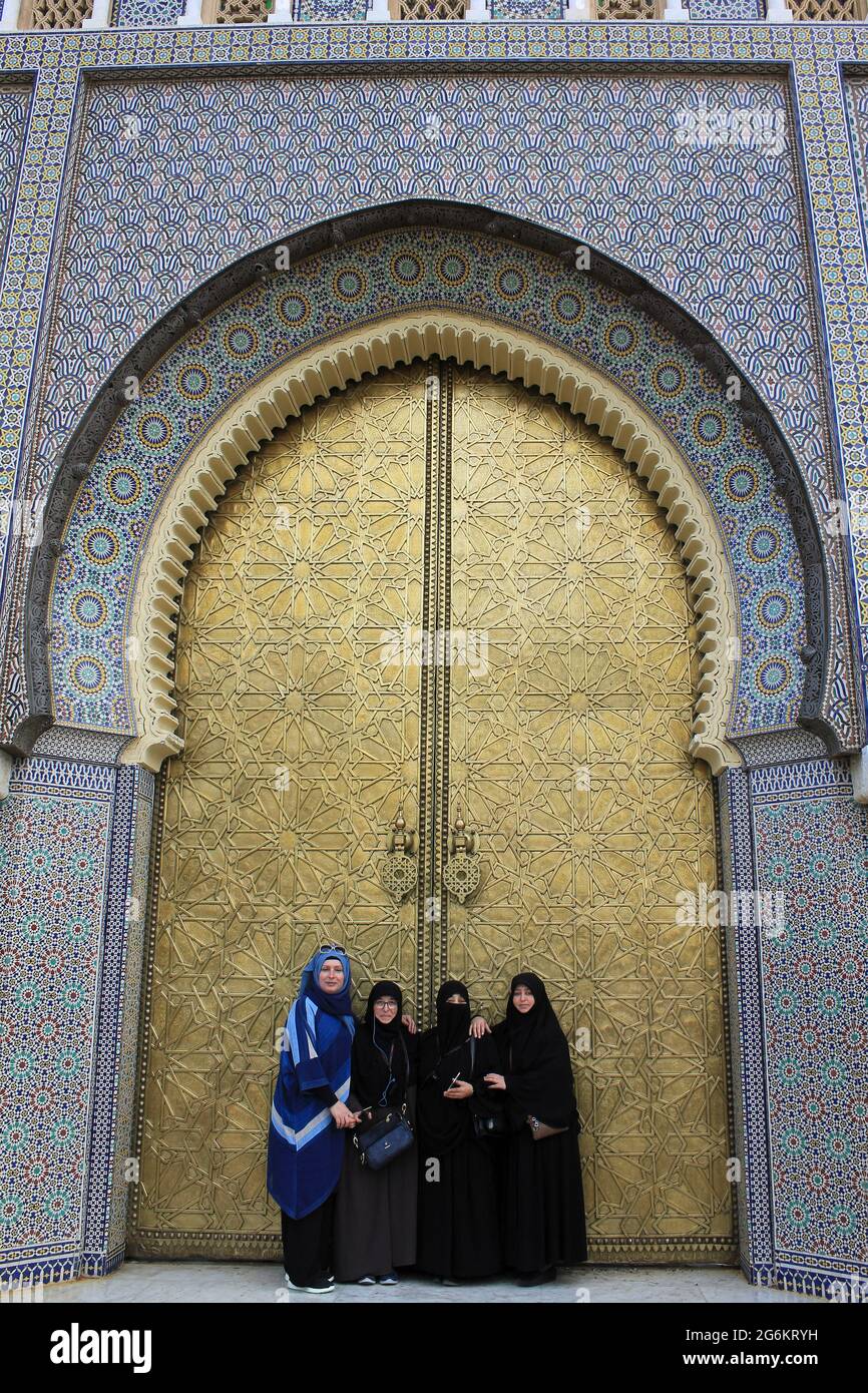 Femmes musulmanes debout devant une grande porte en laiton au Palais Royale de Fès, au Maroc Banque D'Images