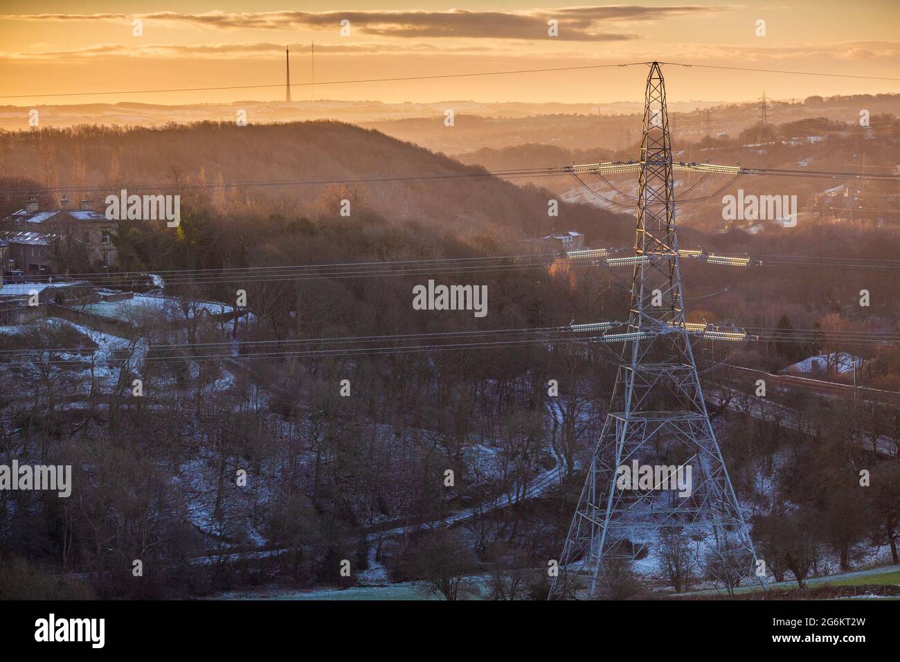 Un matin hivernal froid près de Halifax avec un réseau électrique pylône et un mât Emley Moor éloigné tandis que le soleil se lève au-dessus des Pennines. Banque D'Images