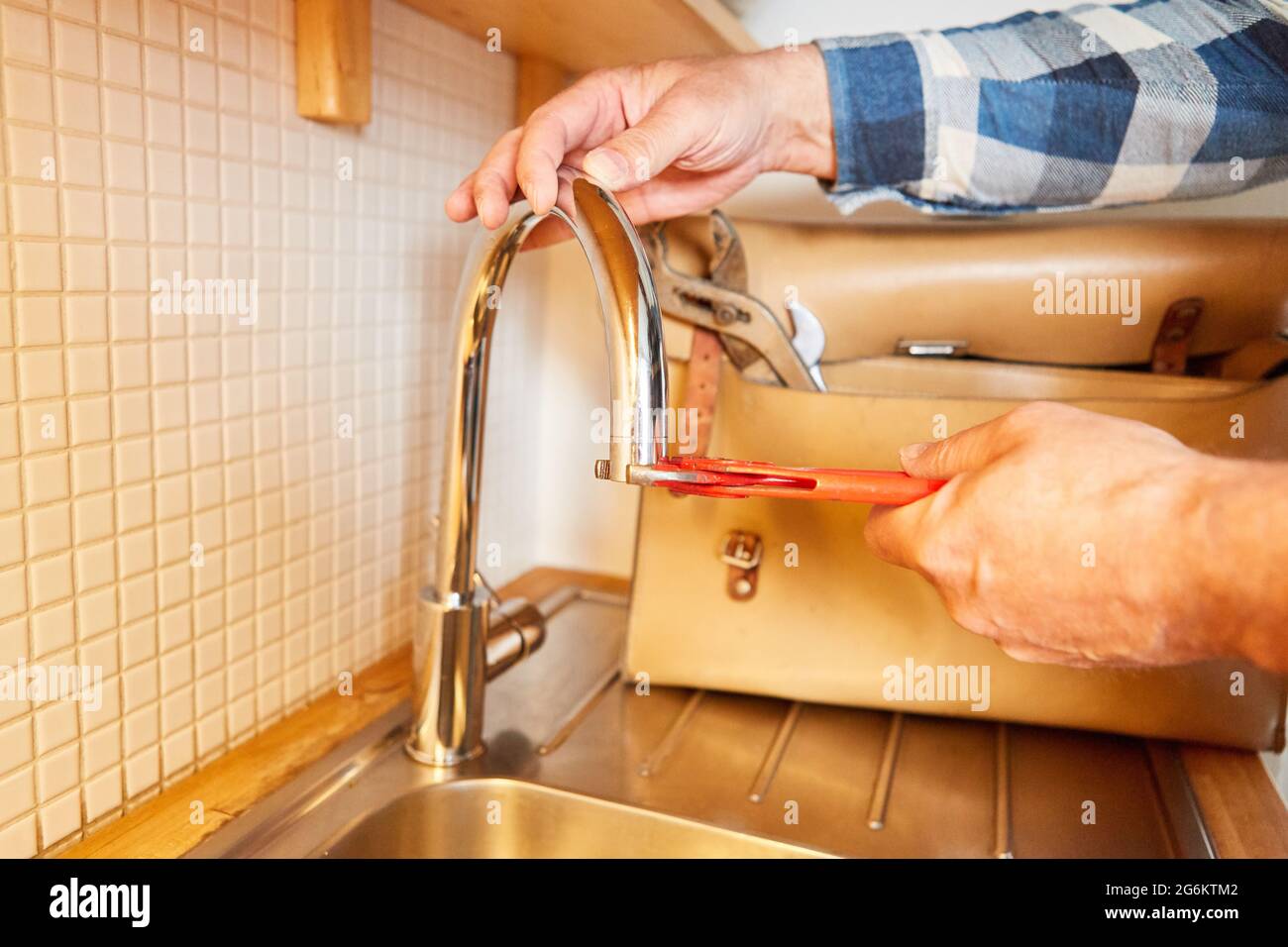 Le plombier avec une clé à pipe change la buse de mélange du robinet dans l'évier de cuisine Banque D'Images