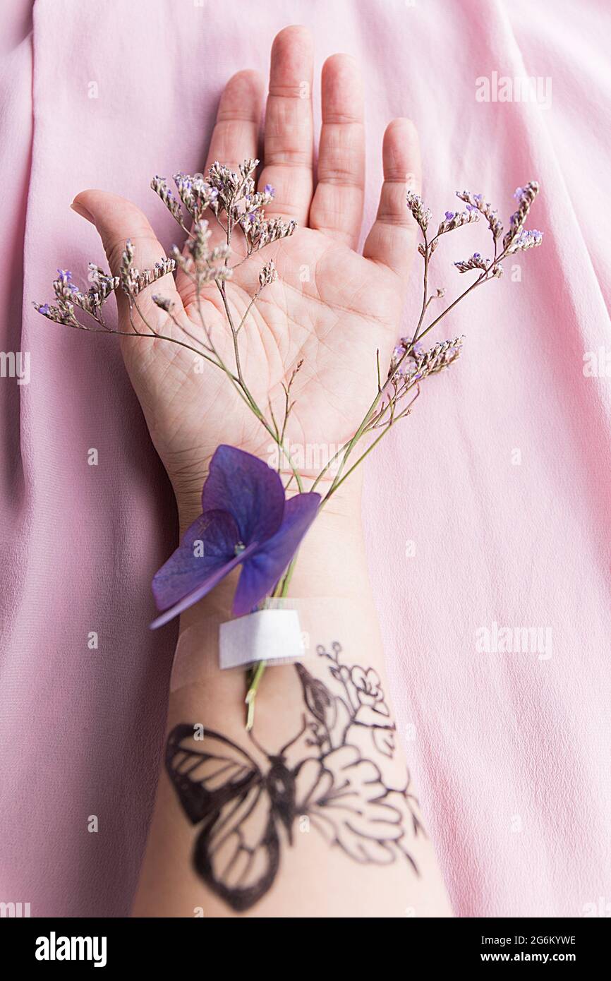 bras avec tatouages et fleurs sauvages Banque D'Images