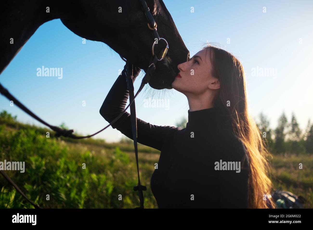 Jeune belle femme prenant soin de son cheval l'embrassant. Banque D'Images