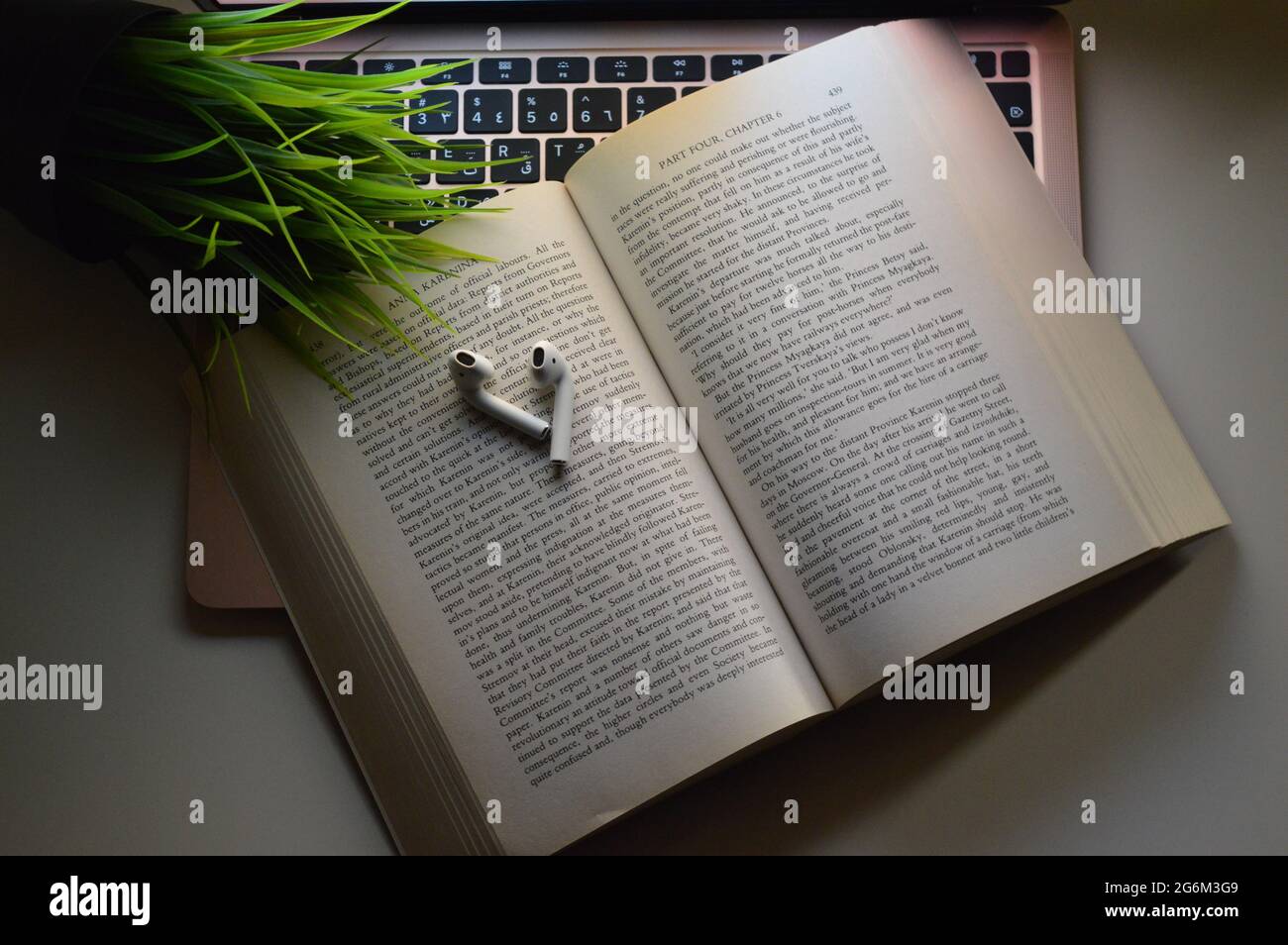 apple MacBook, AirPods et un livre. La photo a été prise à l'aide de la lumière du MacBook. Banque D'Images