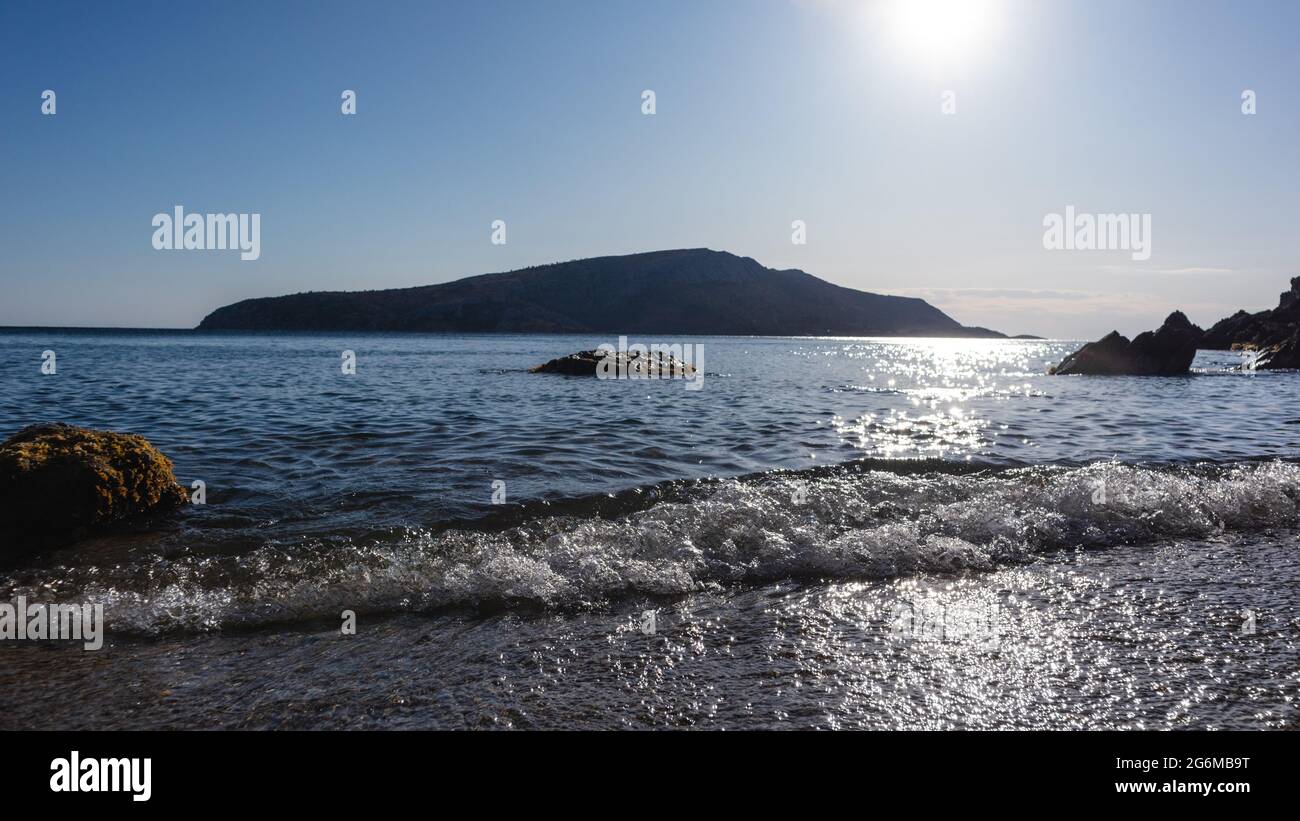 Soleil éclatant sur la côte sauvage avec des vagues calmes. Mer Méditerranée avec silhouettes de rochers, eau claire et sunbeam. Voyagez en Grèce près d'Athènes. Assaisonnement d'été Banque D'Images