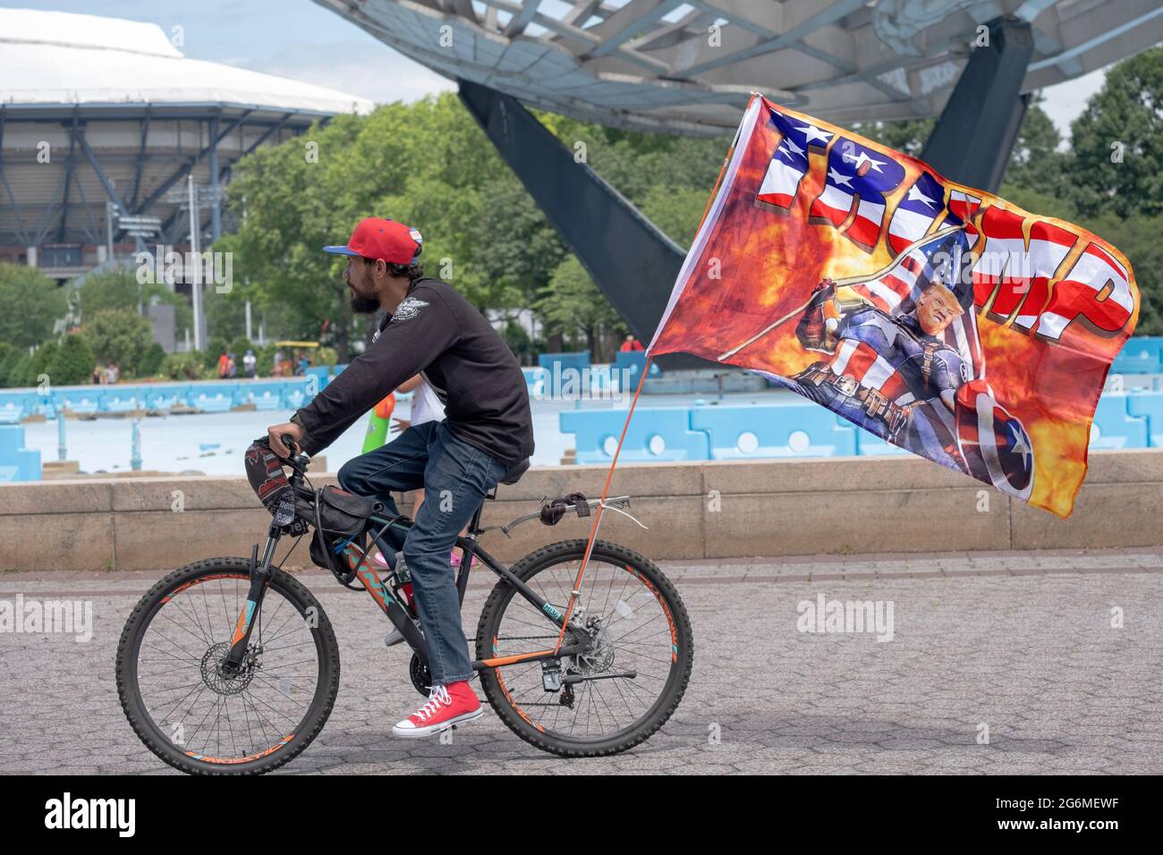 Un supporter dominicain de Trump conduit son vélo affichant une grande bannière de Trump. Près de Unisphere à Flushing Meadows, Queens, New York. Banque D'Images Un supporter dominicain de Trump conduit son vélo affichant une grande bannière de Trump. Près de Unisphere à Flushing Meadows, Queens, New York. Banque D'Images