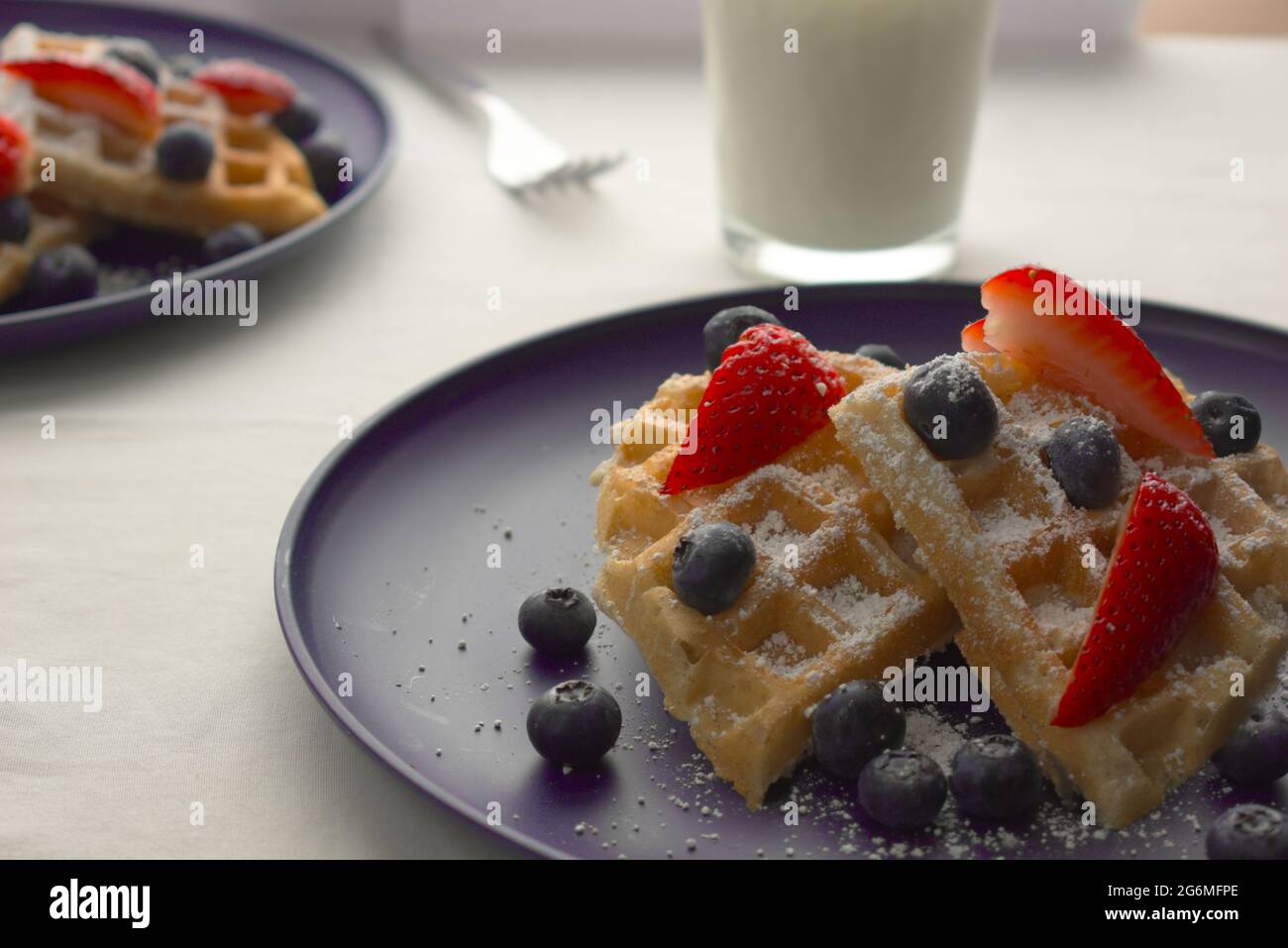 Un petit-déjeuner composé de gaufres fraîches et de baies variées sur le dessus. Le tout sous une fine couverture de sucre en poudre. Banque D'Images