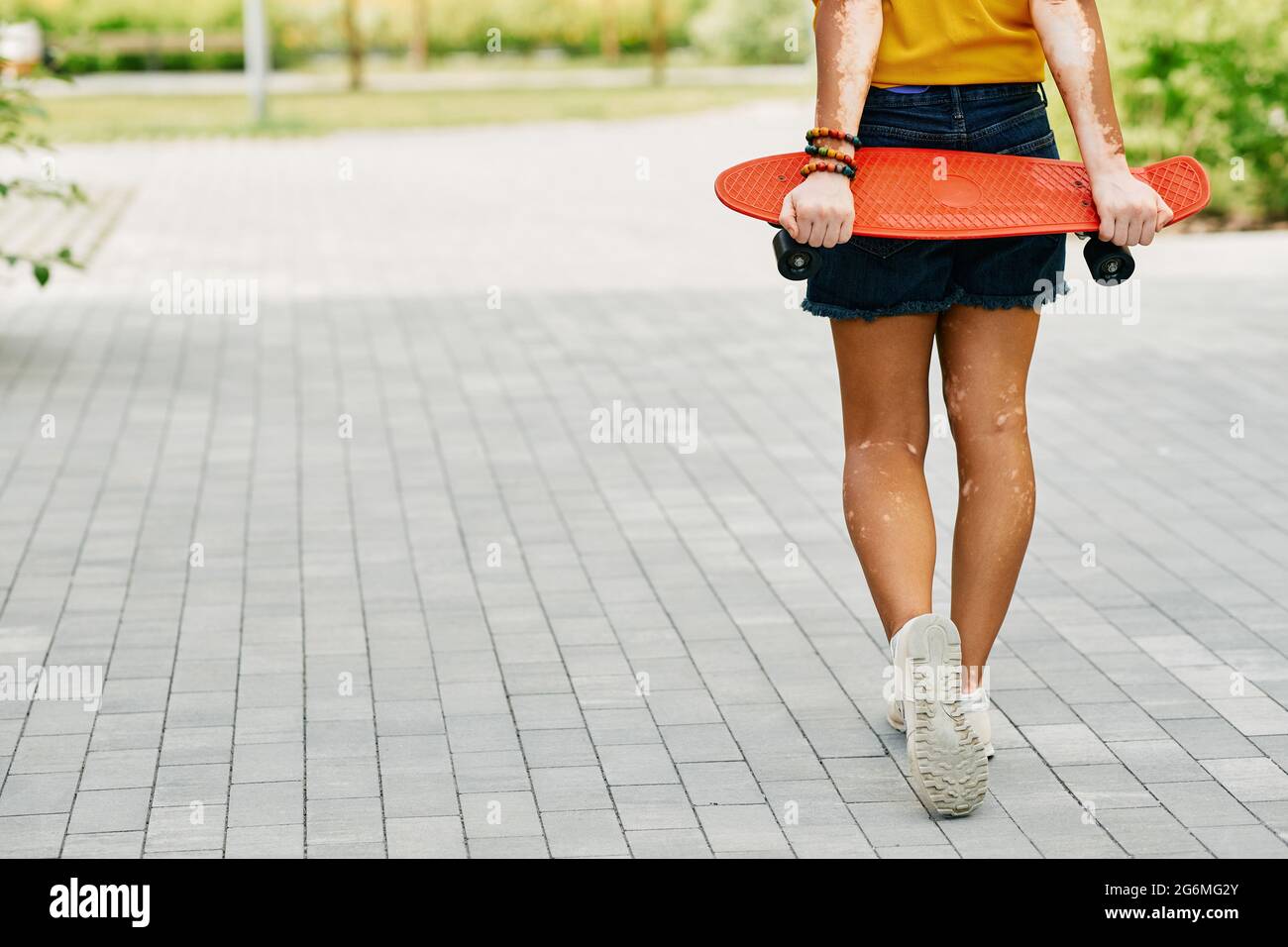 Vue arrière d'une patineuse de fille se dresse avec tableau de sou rouge au parc de la ville. Activité style de vie, culture de la jeunesse Banque D'Images
