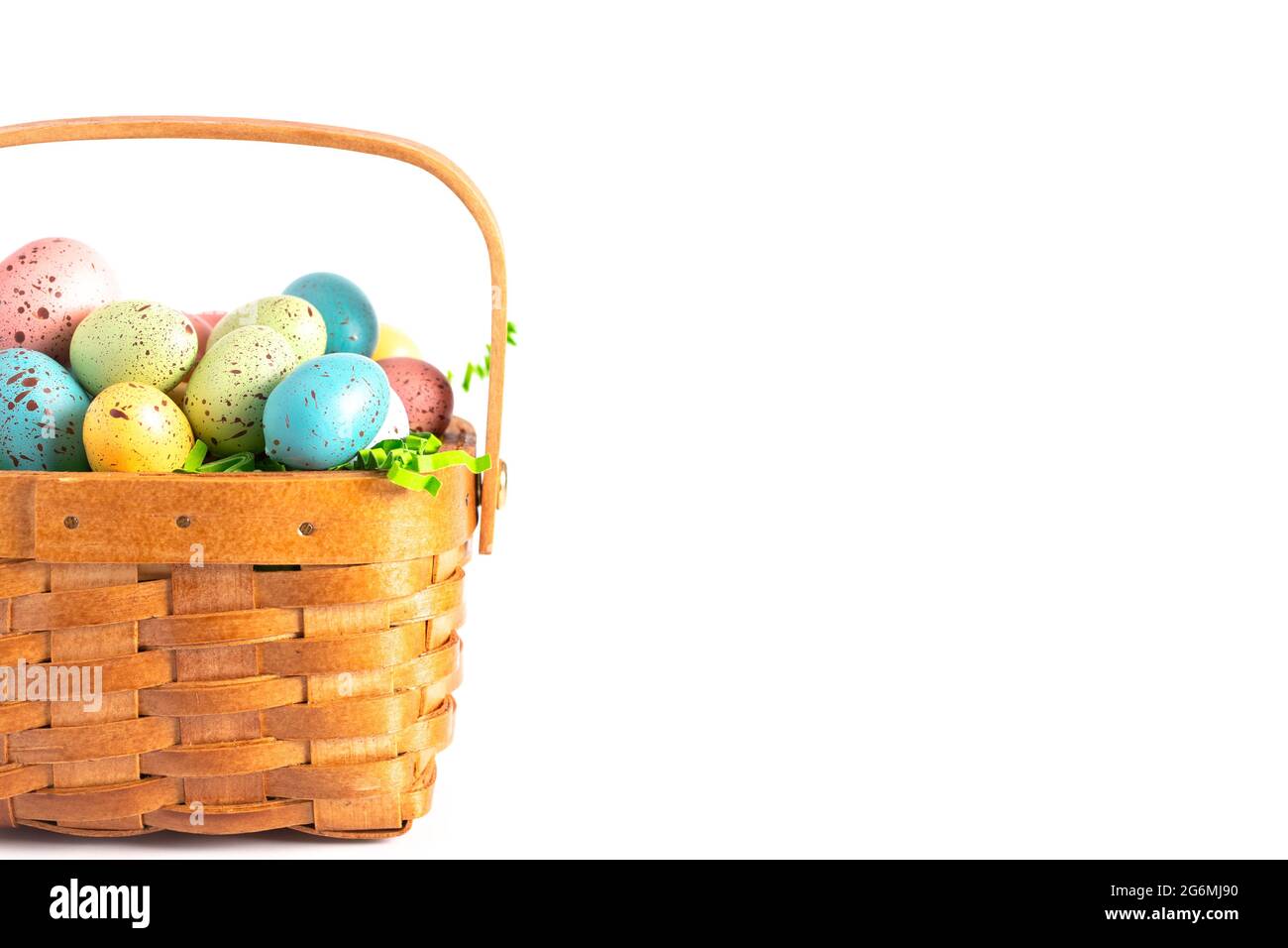 Un panier de Pâques en bois rempli d'œufs décorés isolés sur un fond blanc Banque D'Images