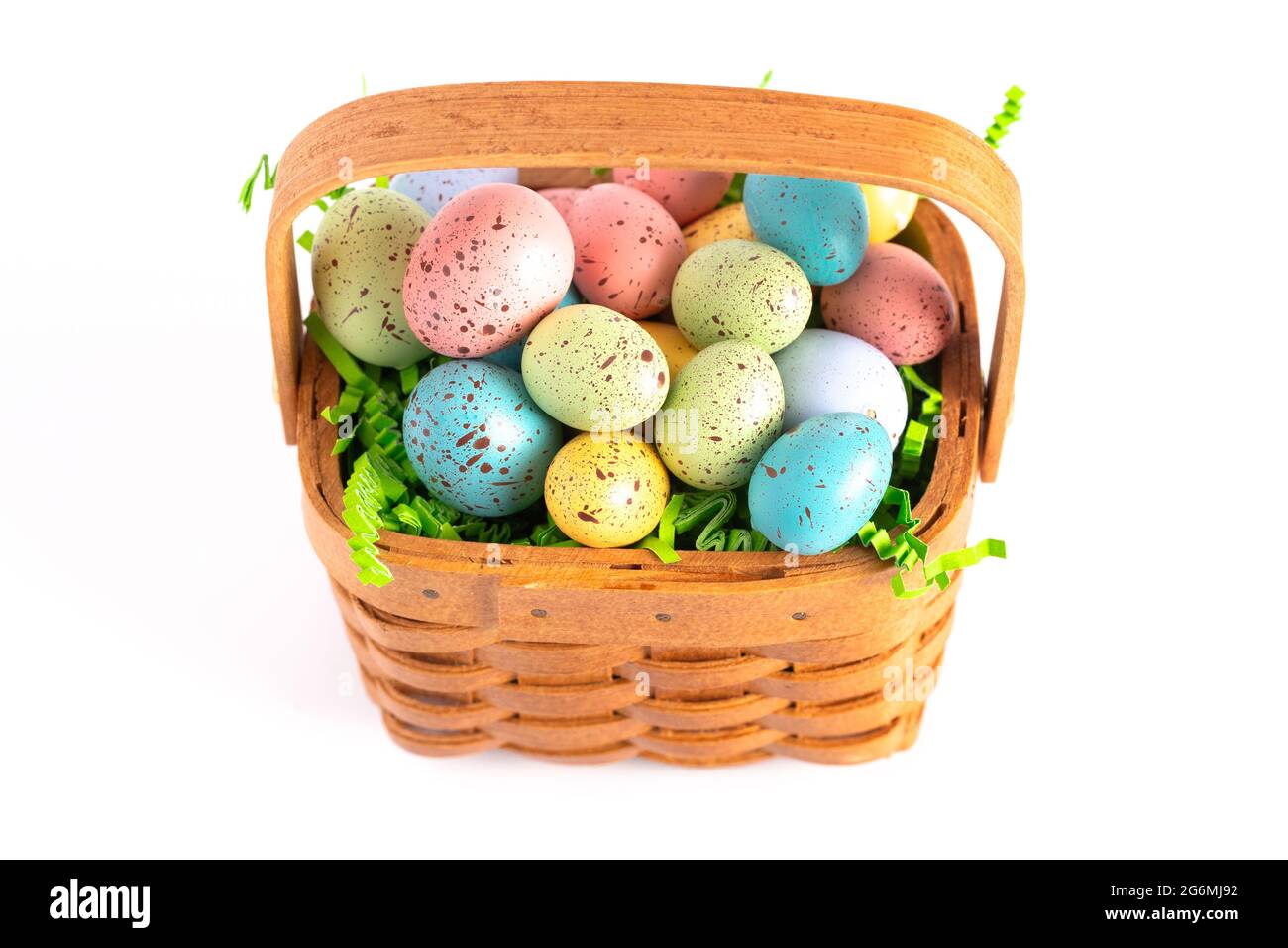 Un panier de Pâques en bois rempli d'œufs décorés isolés sur un fond blanc Banque D'Images