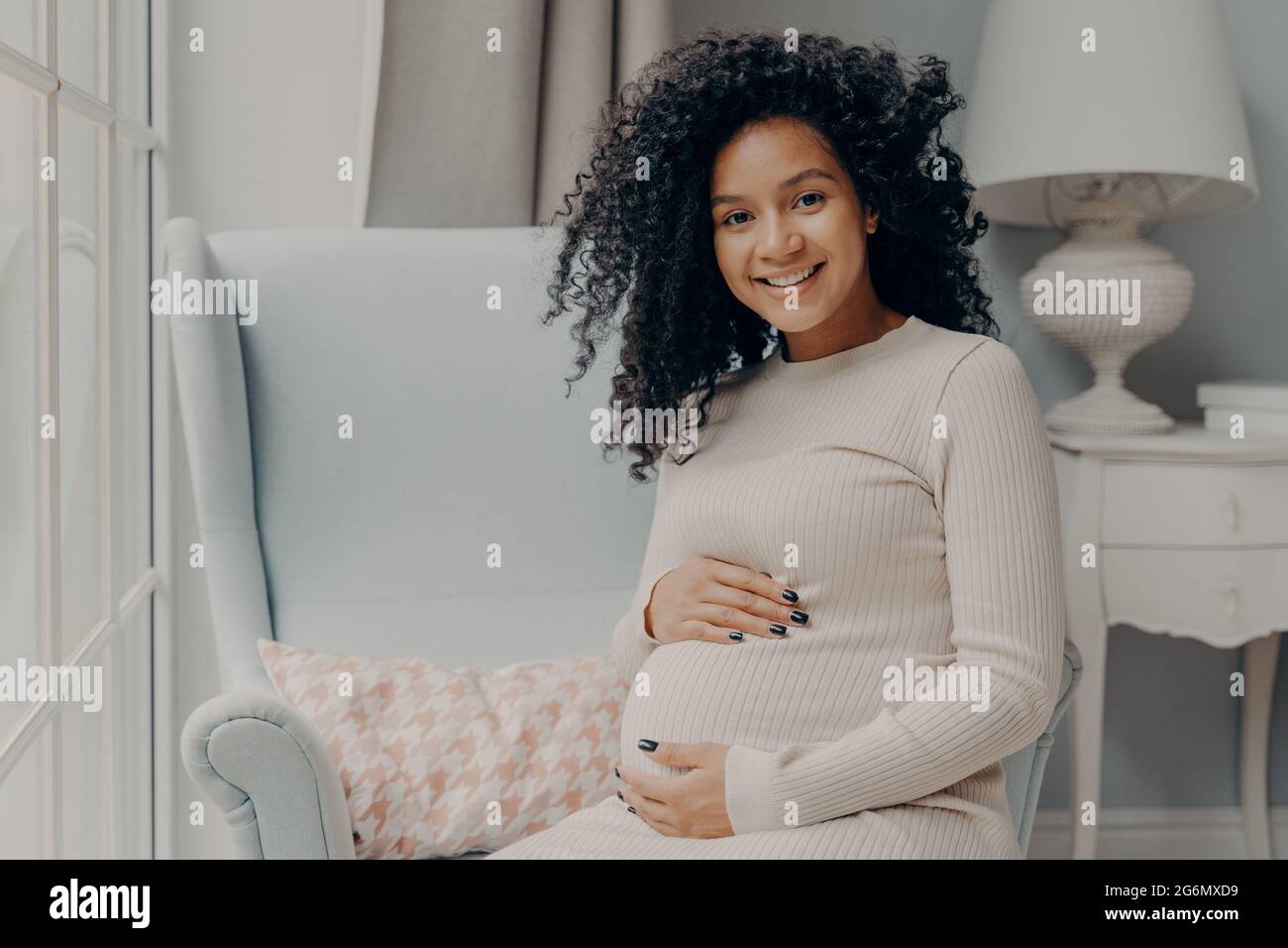 Belle femme enceinte africaine profitant de la grossesse, passant du temps à la maison Banque D'Images