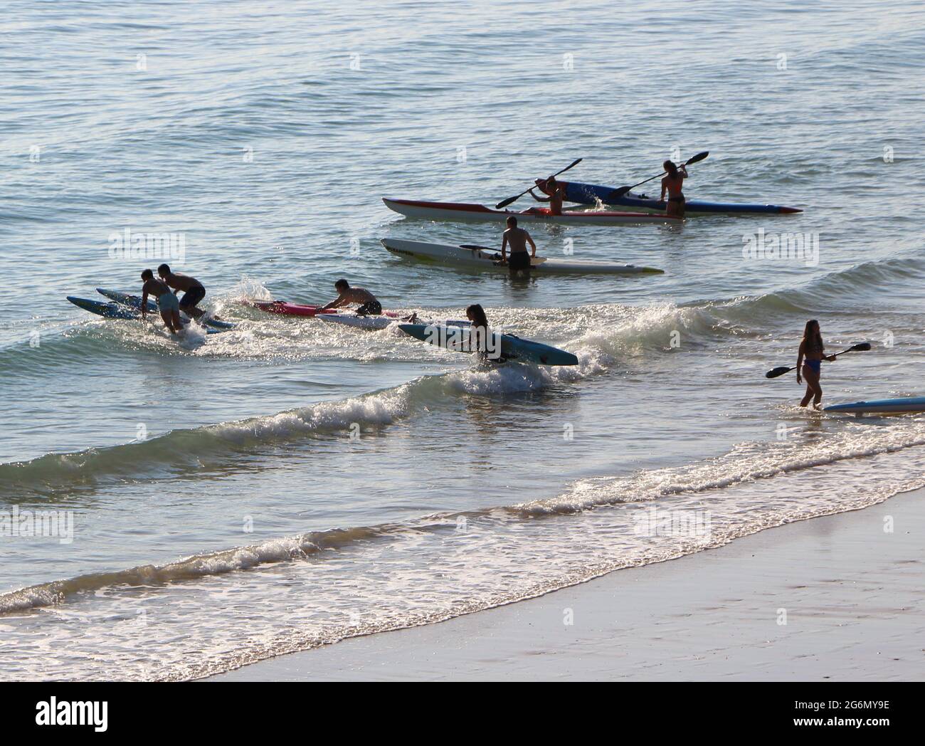 Jeunes avec planches de surf et skis de surf entrant dans l'océan lors d'un matin ensoleillé de printemps Sardinero Santander Cantabria Espagne Banque D'Images
