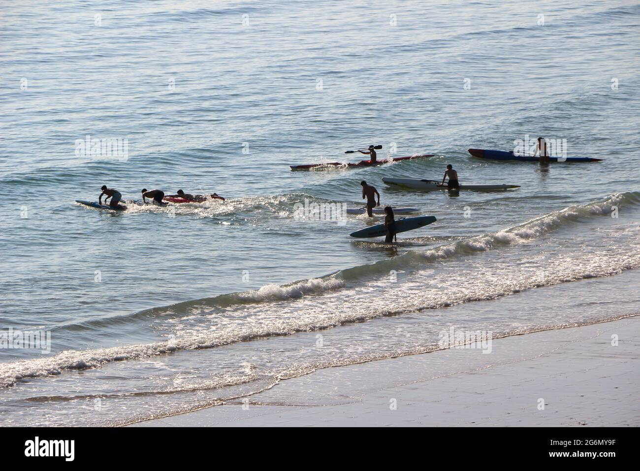 Jeunes avec planches de surf et skis de surf entrant dans l'océan lors d'un matin ensoleillé de printemps Sardinero Santander Cantabria Espagne Banque D'Images