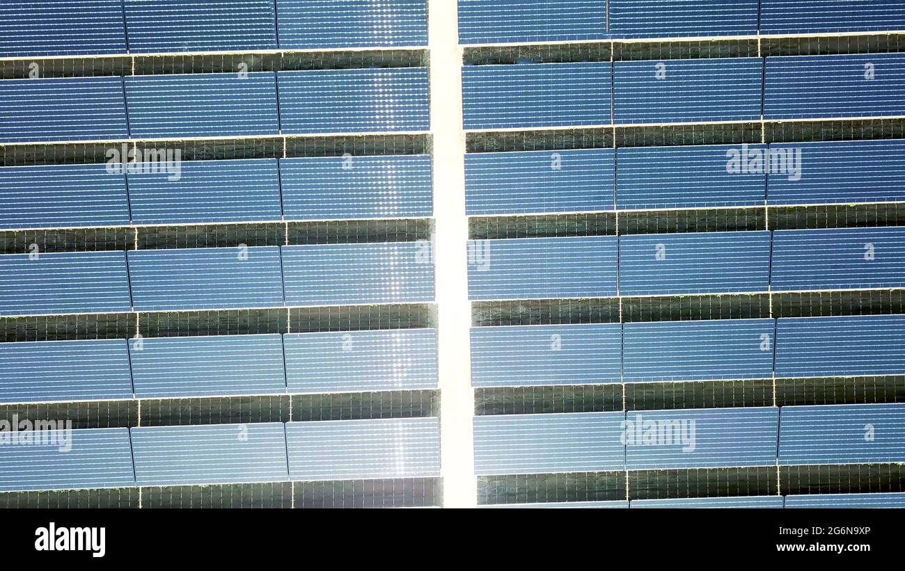 Panneaux d'énergie solaire de l'antenne de drone au-dessus de la vue. Réflexion de la lumière du soleil sur les modules photovoltaïques dans le fond de la ferme de centrale d'énergie solaire. Banque D'Images