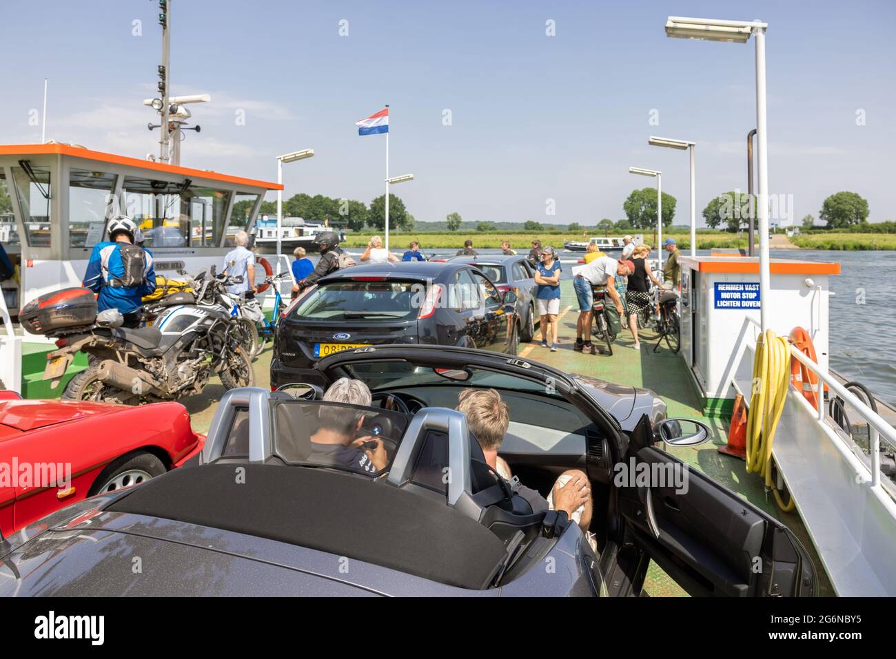 Ferry avec voitures, vélos et piétons près du village hollandais de Cuijk Banque D'Images