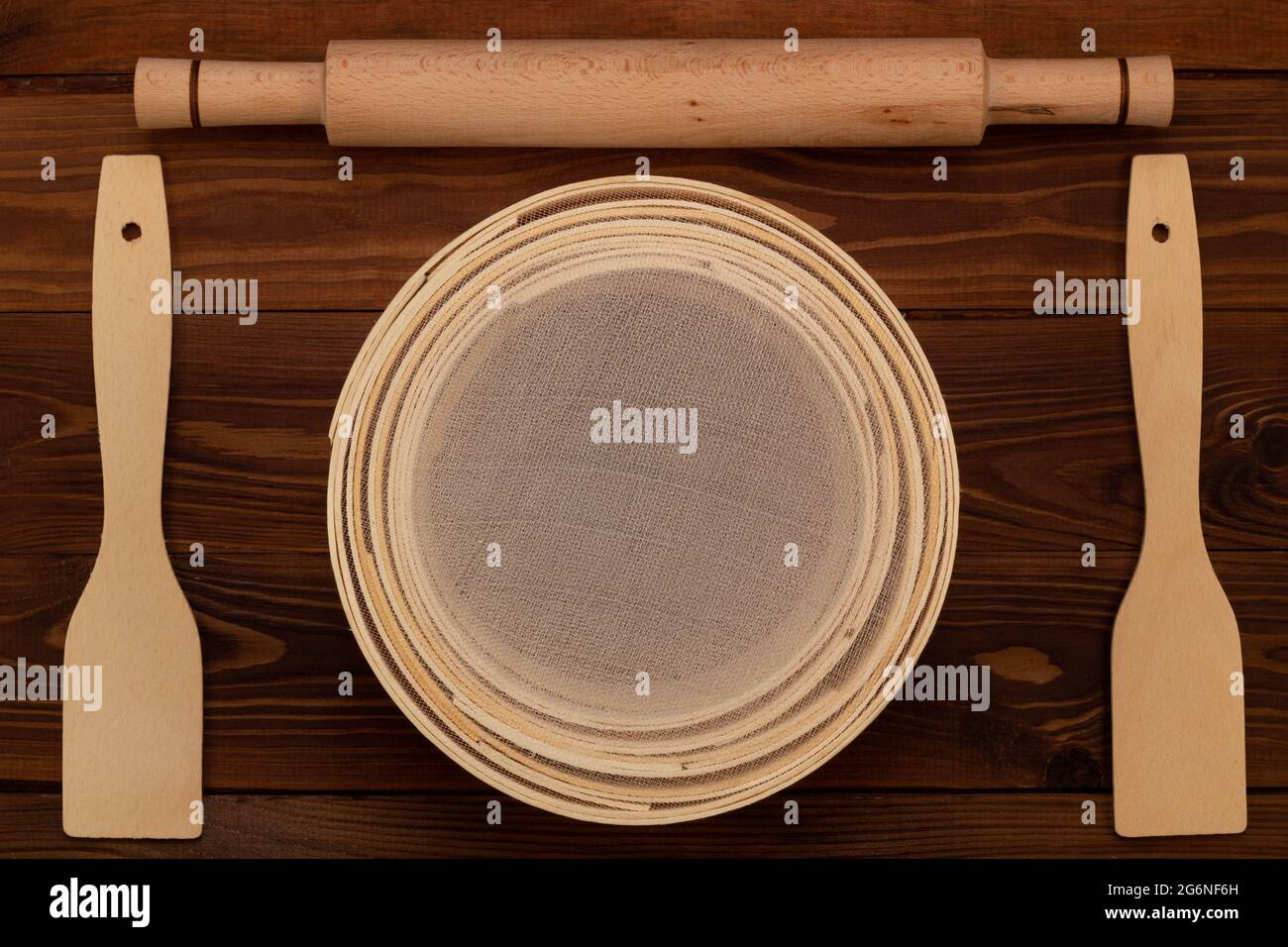 Tamis à farine traditionnel antique, en bois de hêtre et maille fine, broche à pâte et spatules culinaires sur fond marron. Réglé pour sifti Banque D'Images