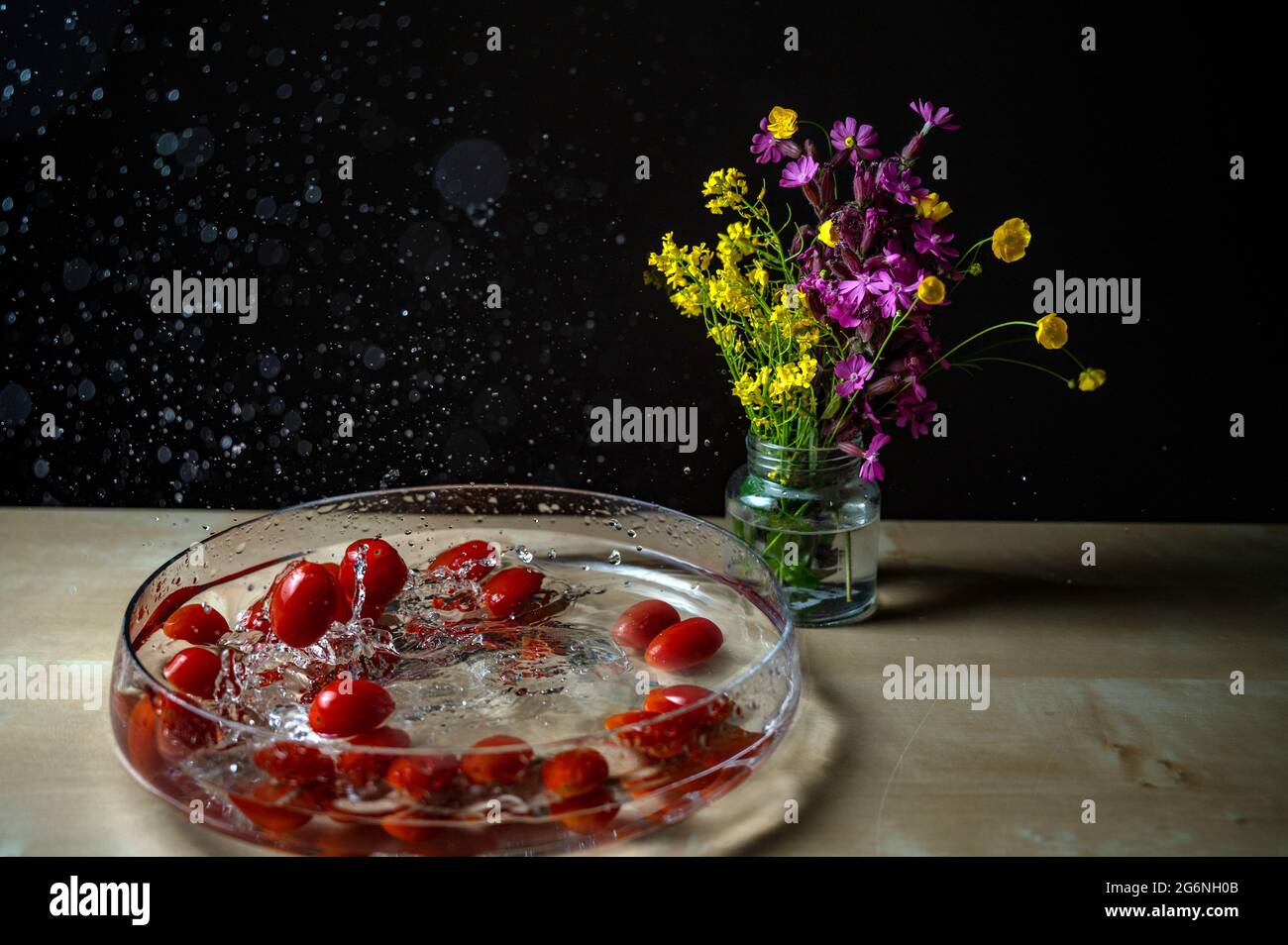 Gros plan de tomatos de prune de bébé biologique rouge frais (tomate de bébé, tomate de cerise) le groupe tombant sur le bol d'eau avec l'eau splash copyspace fleur backgro Banque D'Images
