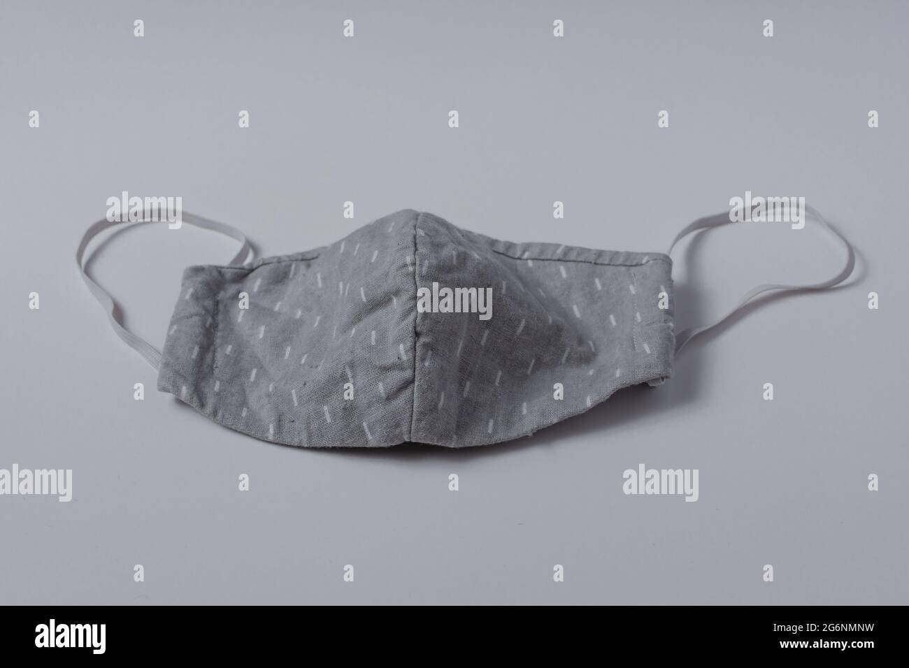 Masque gris fait maison avec bandes blanches et élastiques isolés sur fond blanc Banque D'Images