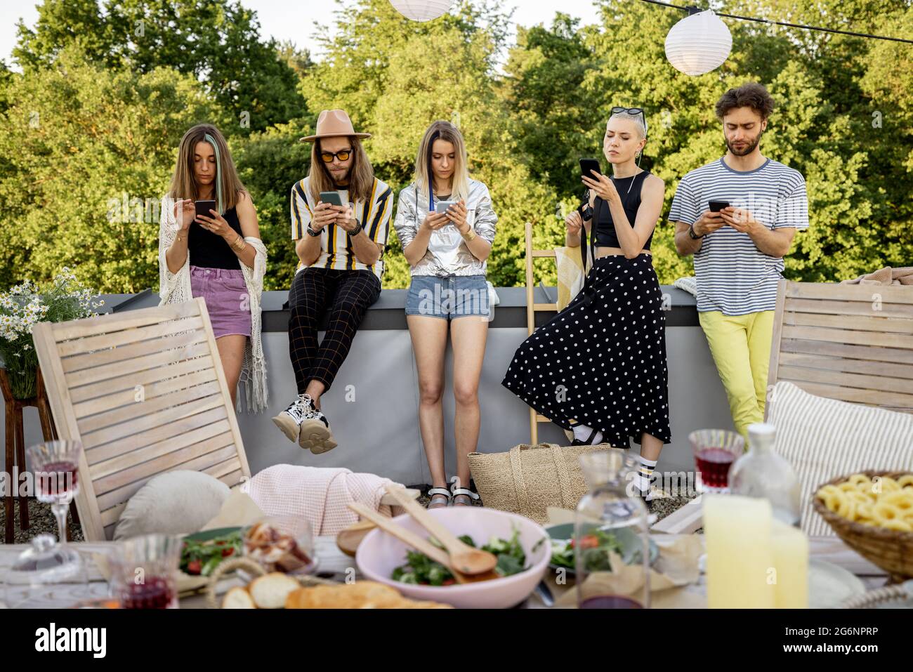 Les gens passent du temps ensemble, assis séparément dans un smartphone lors d'une fête à l'extérieur Banque D'Images