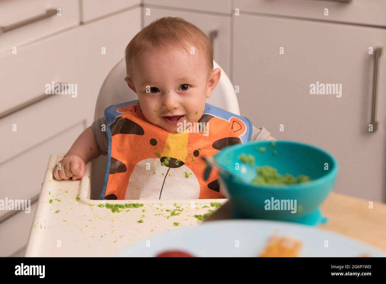 Un bébé de 6 mois mangeant de la nourriture dans une chaise haute Banque D'Images