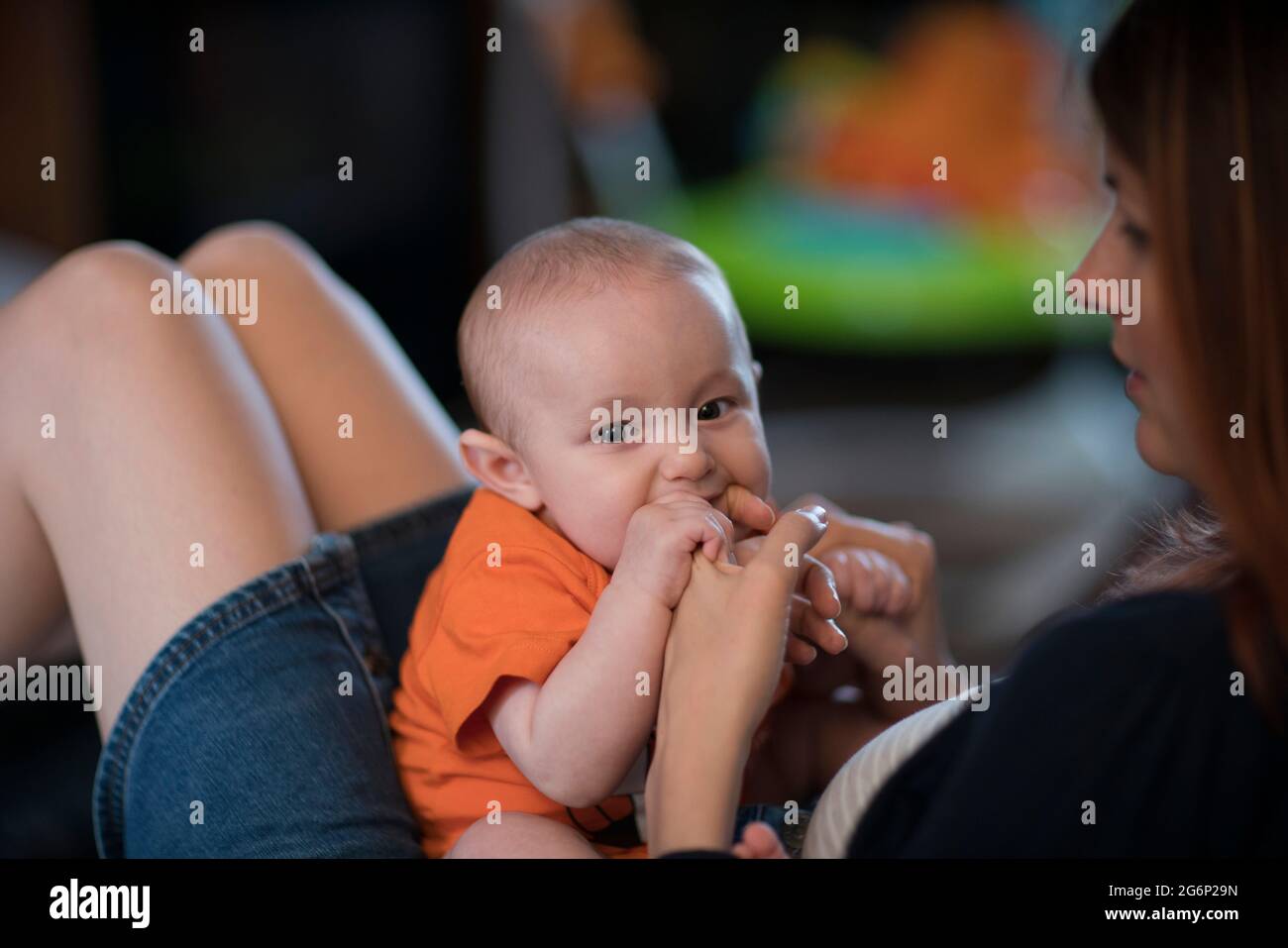 Un bébé qui mord le doigt de sa mère Banque D'Images