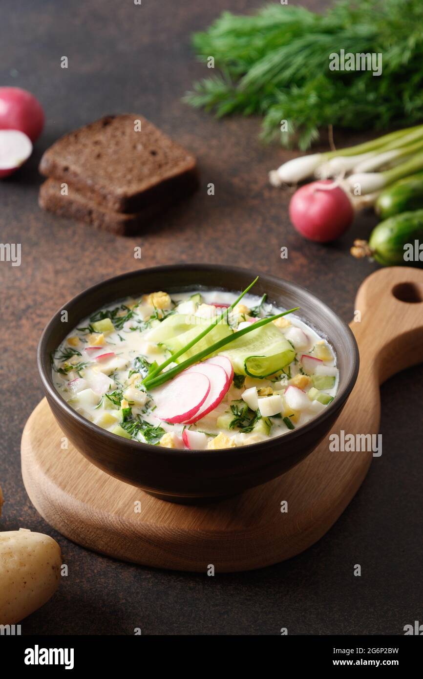 Soupe d'été maison à l'Okroshka avec kéfir, servie avec du pain de seigle et des légumes frais sur une table sombre. Format vertical. L'Okroshka traditionnel est un russe Banque D'Images