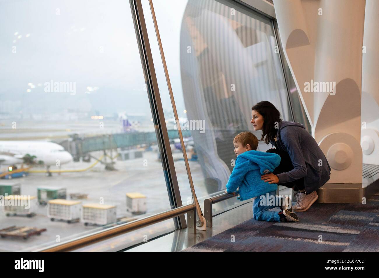 Une mère et un fils regardant les avions par la fenêtre de l'aéroport Banque D'Images