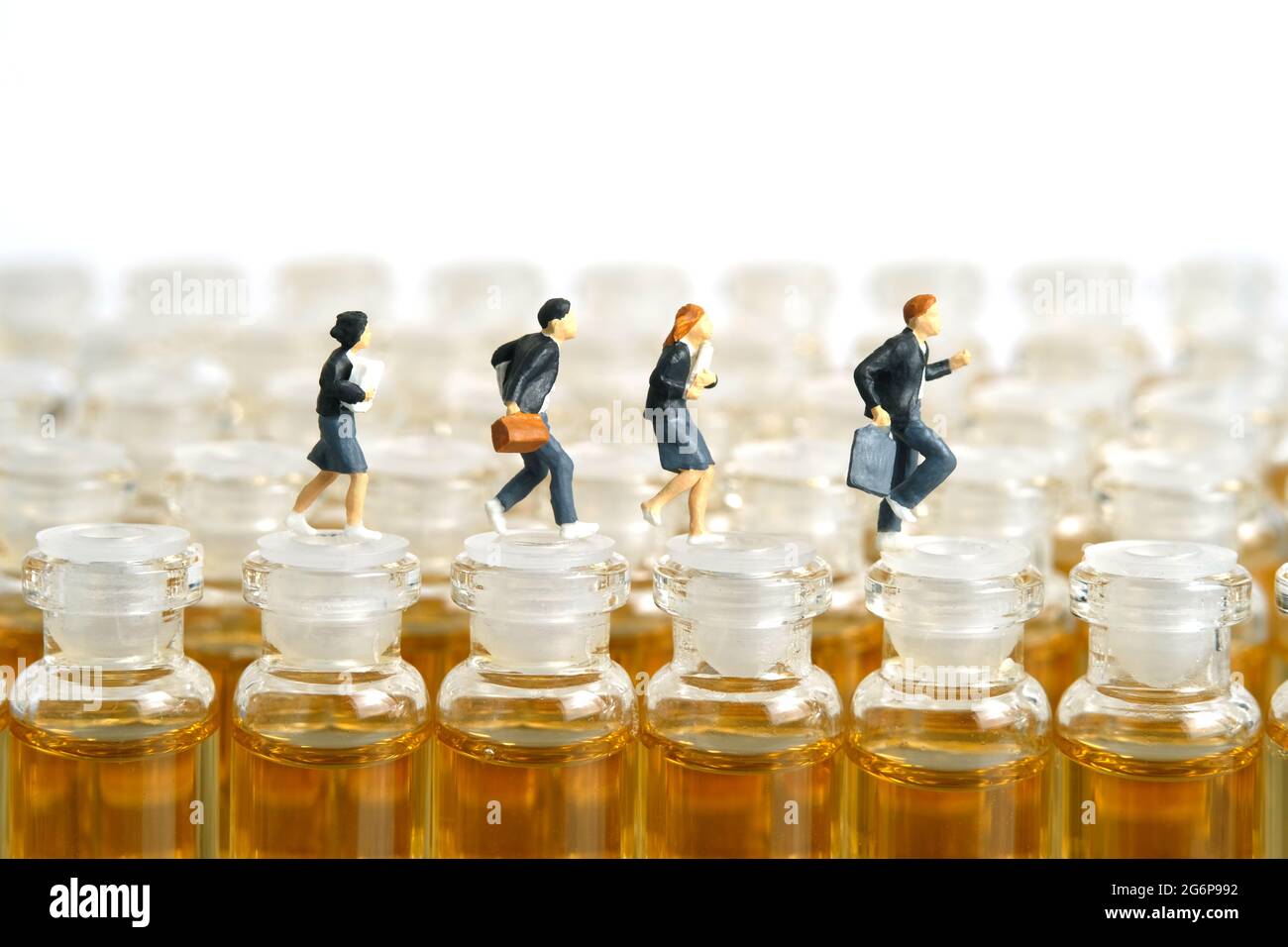 Photographie miniature de personnage de jouet de personnes. Concept de vaccination des adolescents. Un groupe d'élèves de premier cycle du secondaire courant au-dessus de l'ampoule du vaccin b Banque D'Images