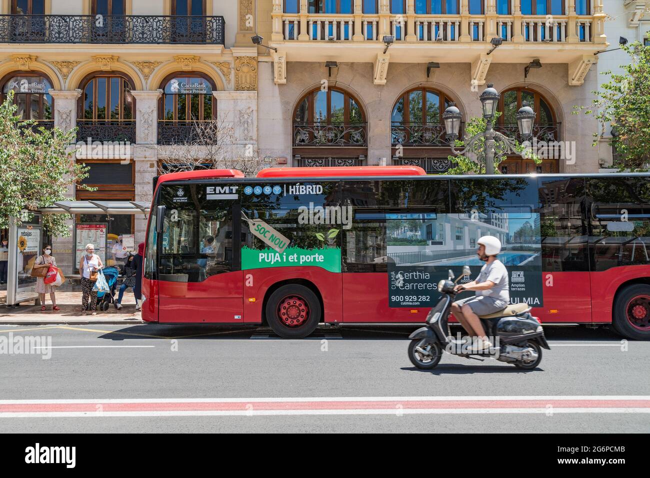 Valence, Espagne. 06e juillet 2021. Un homme passe un scooter devant un bus  à un arrêt de bus. La Société de transport municipal (Empresa Municipal de  Transports, EMT) de Valence a réduit