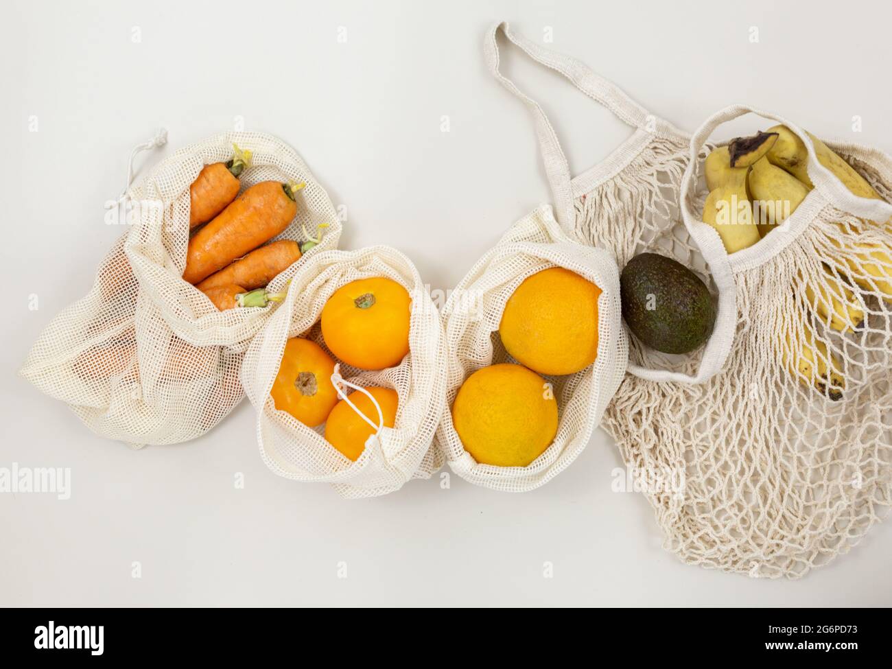 Fruits frais, légumes dans des sacs de coton écologique sur une table beige. Carottes, oranges, bananes, avocat du marché. Concept d'achat sans gaspillage. Banque D'Images