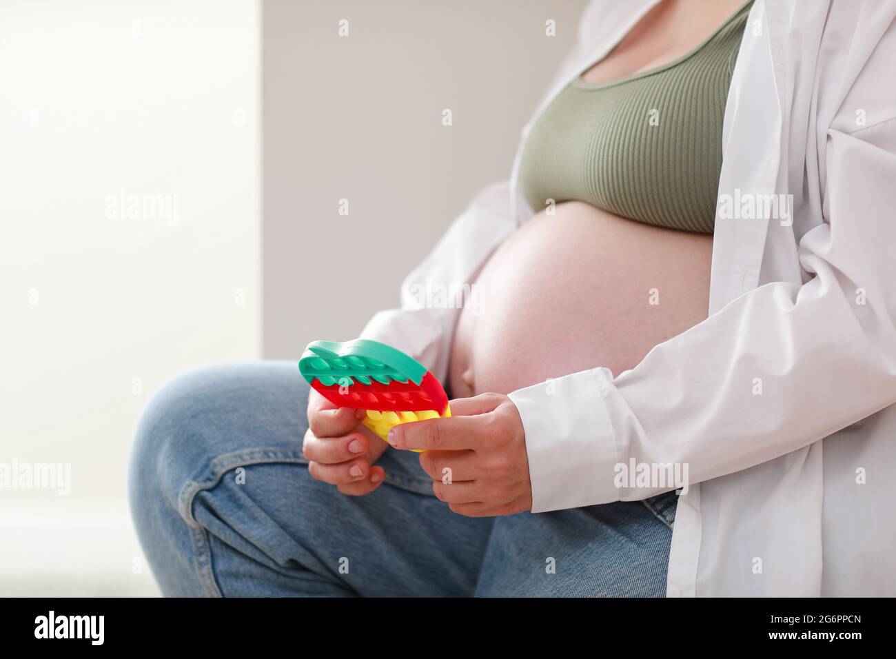 femme enceinte avec grand ventre avancé grossesse est en utilisant pop il  jouet sensoriel. fille appuie sur des bulles de silicone colorées.  Soulagement du stress et de l'anxiété. Tr Photo Stock 