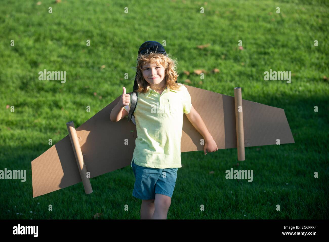 Les enfants volent. Drôle enfant garçon avec les pouces vers le haut  sourire porter chapeau pilote et lunettes volant avec jouet carton ailes  d'avion, Start up Freedom concept, insouciant Photo Stock -