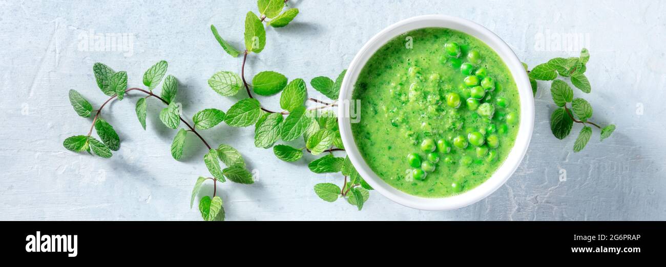 Soupe végétalienne panoramique avec petits pois verts et menthe, plat de dessus plan de pose. Désintoxication printanière saine. Concept de régime biologique de légumes Banque D'Images