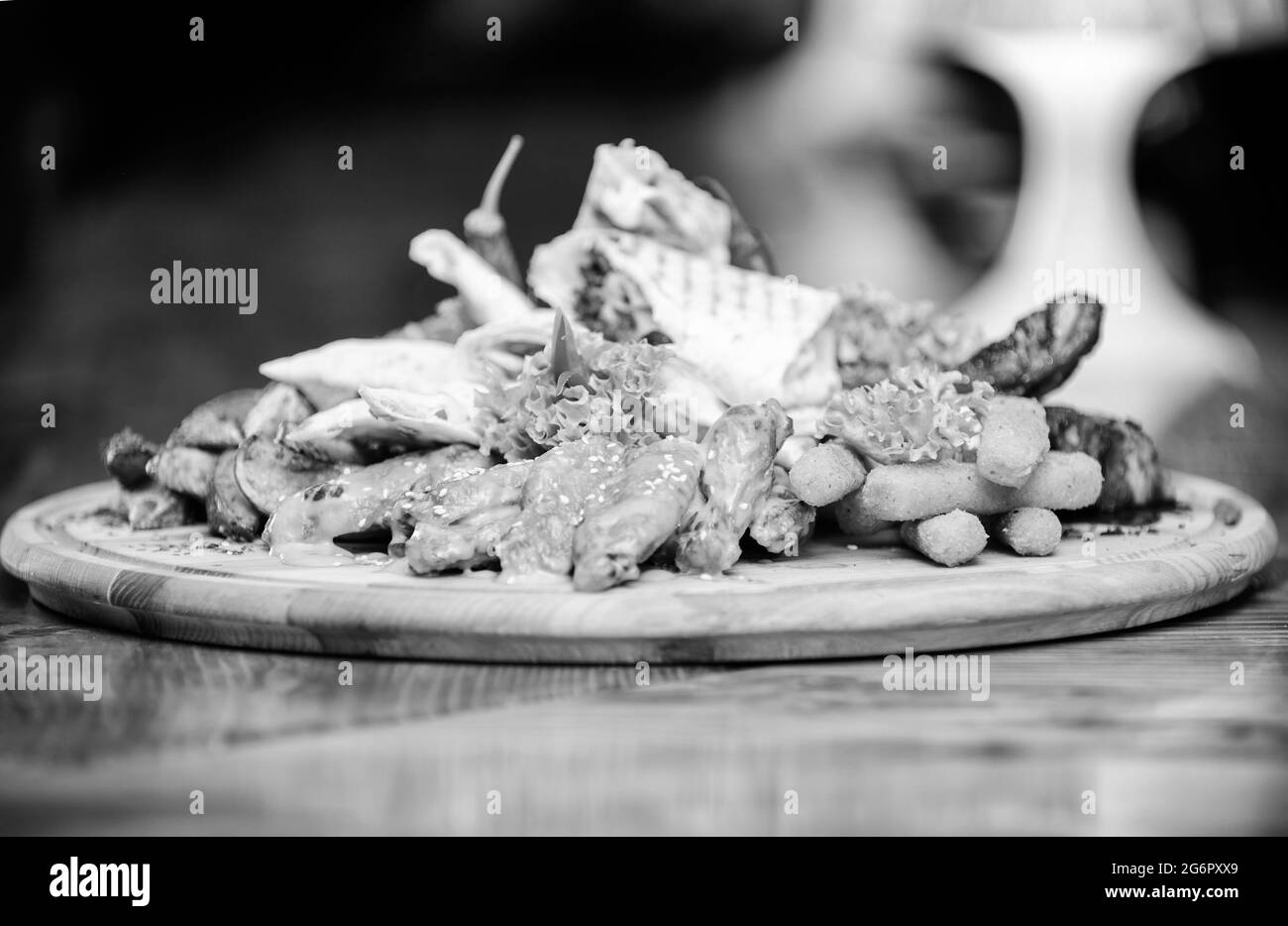 Planche en bois avec beaucoup de frites bâtonnets de poisson burrito et steak de viande servi avec de la salade. En-cas au menu du pub. En-cas à haute teneur en calories pour les amis de groupe. Savoureux Banque D'Images