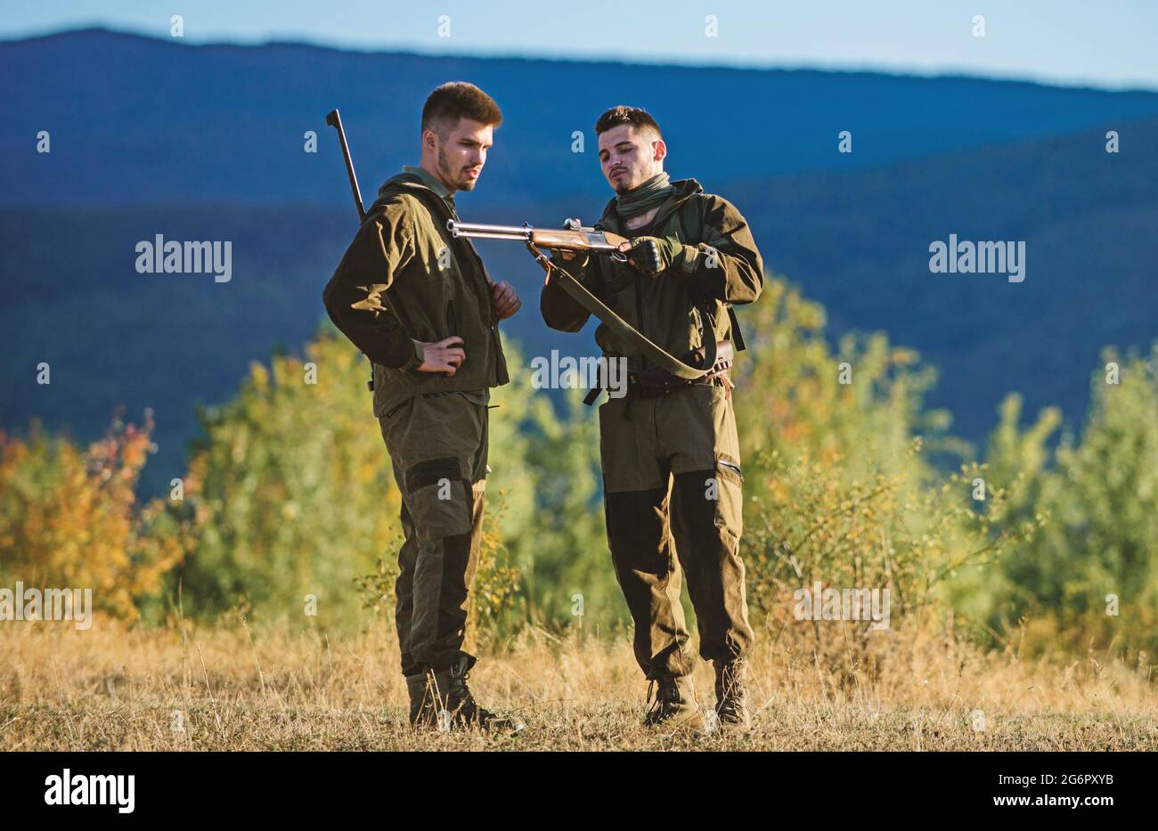 Chasseurs d'homme avec fusil. Camp d'entraînement. Compétences de chasse et équipement d'armes. Comment transformer la chasse en passe-temps. Tenue militaire mode. Amitié des hommes Banque D'Images