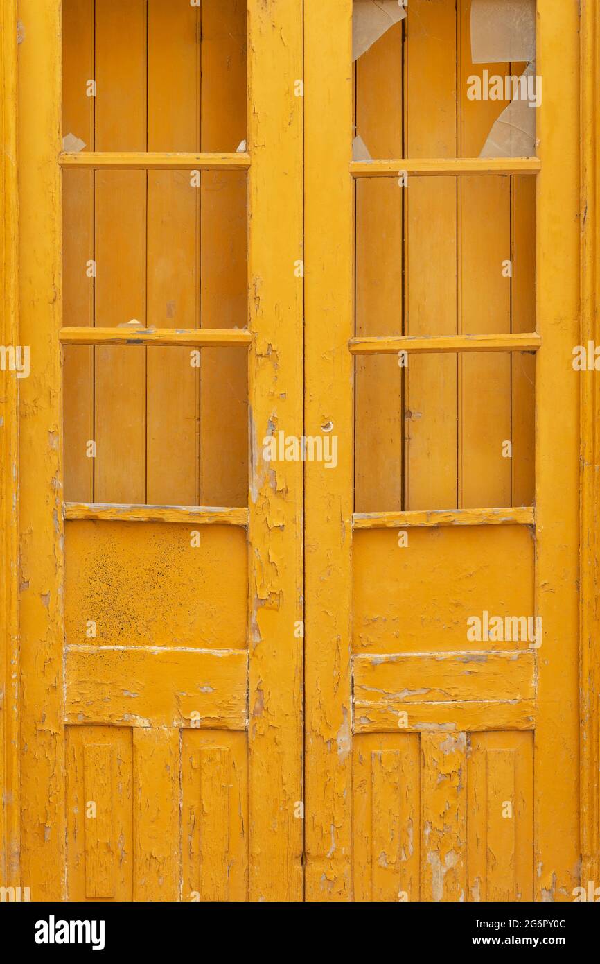 Vue portrait d'une porte jaune et volets en besoin de restauration dans une ville, Portugal Banque D'Images