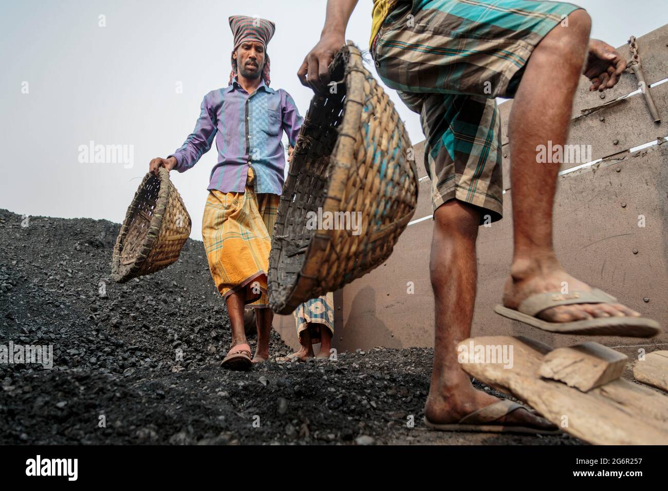 Une chaîne humaine de porteurs transporte du charbon, du sable et du gravier depuis les barges amarrées à la station d'atterrissage d'Aminbazar, sur le fleuve Buriganga, à l'extérieur de Dhaka. Le Bangladesh est diplômé de la catégorie des PMA (pays les moins avancés), grâce en grande partie au travail extrêmement difficile de la main-d'œuvre manuelle bon marché. Un porteur fait entre 80 et 140 USD par mois, selon les sites paylab.com et averagesalarysurvey.com Banque D'Images